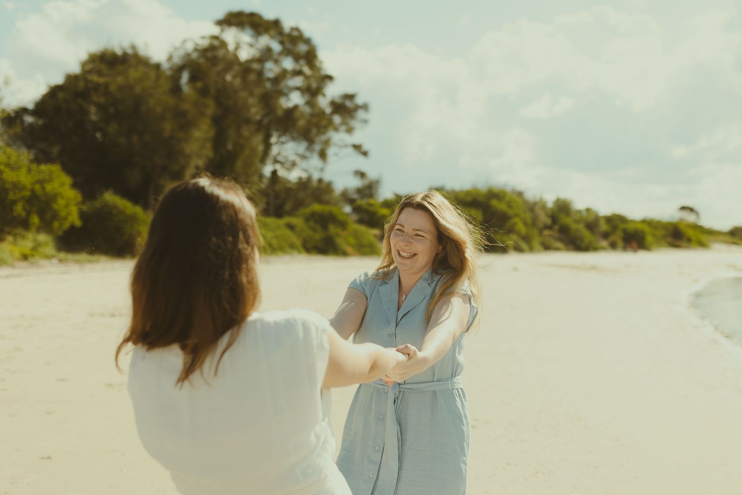 Group enjoying a sunny day walking together on a scenic beach shoreline.