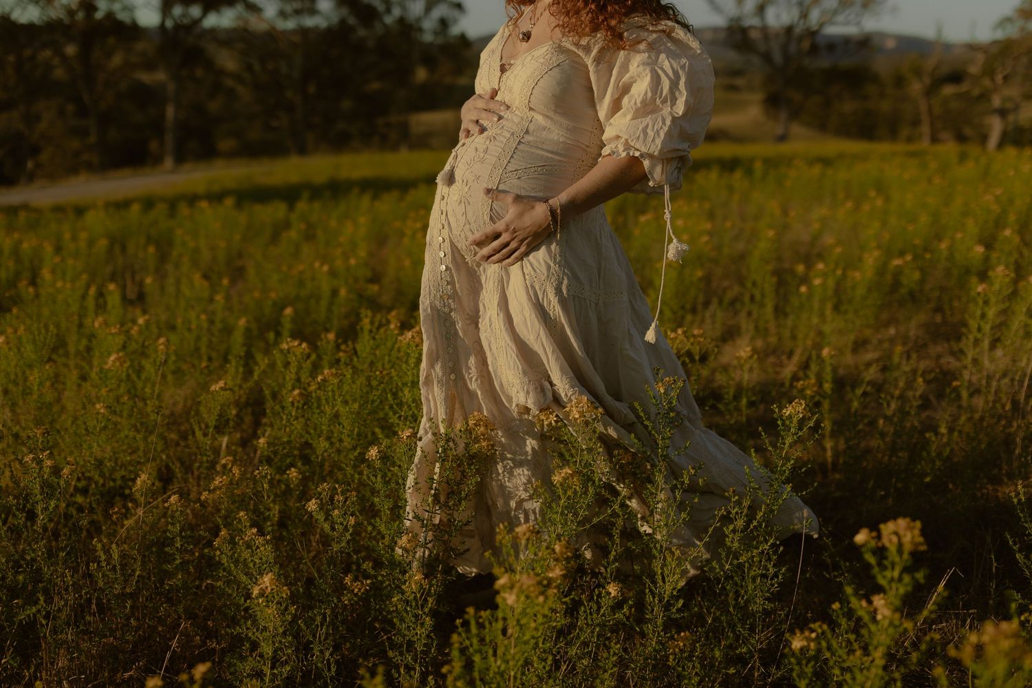 Light-colored figures move through a field of tall yellow flowers at dusk.