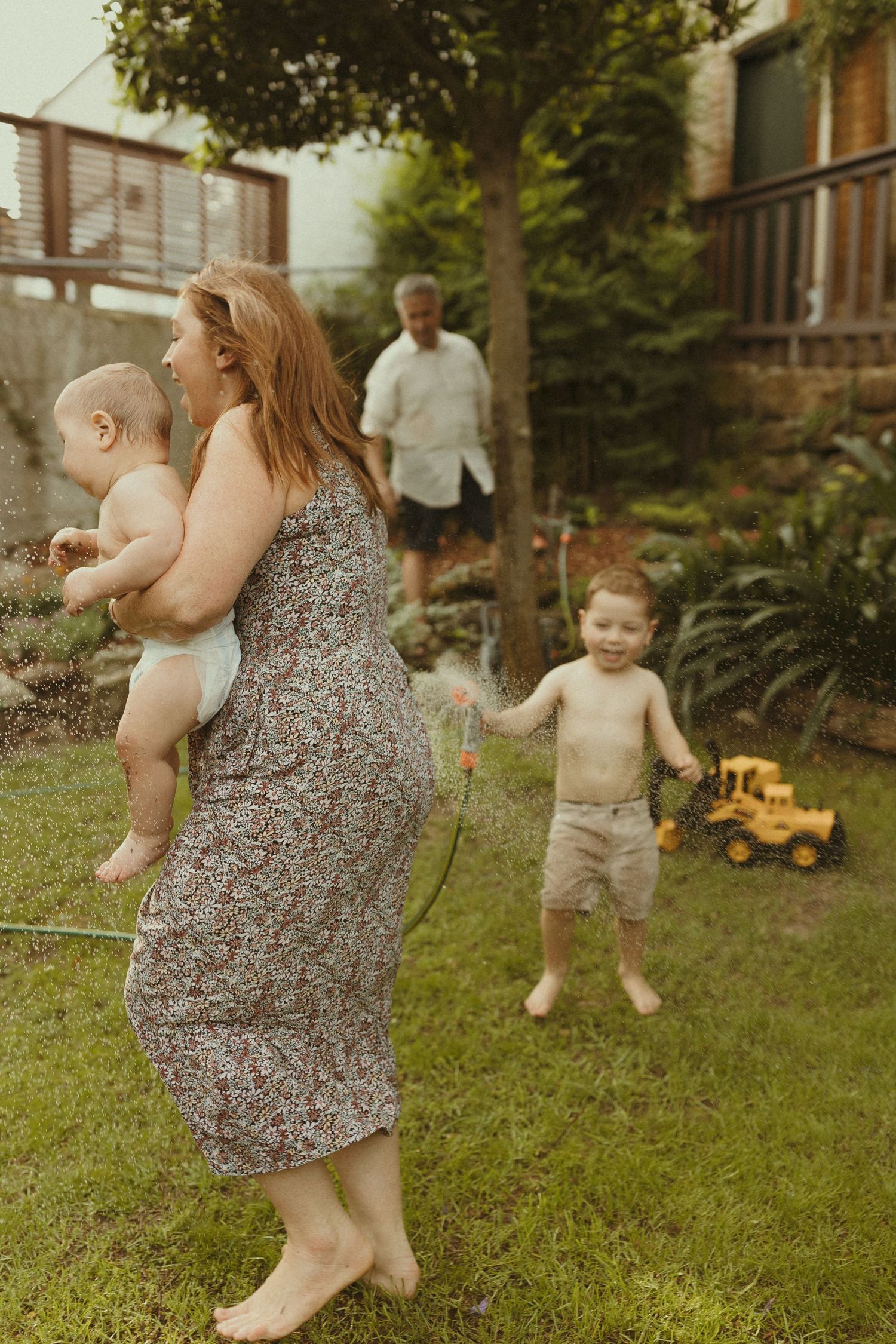 Family playtime in a backyard with toys and natural summer lighting.