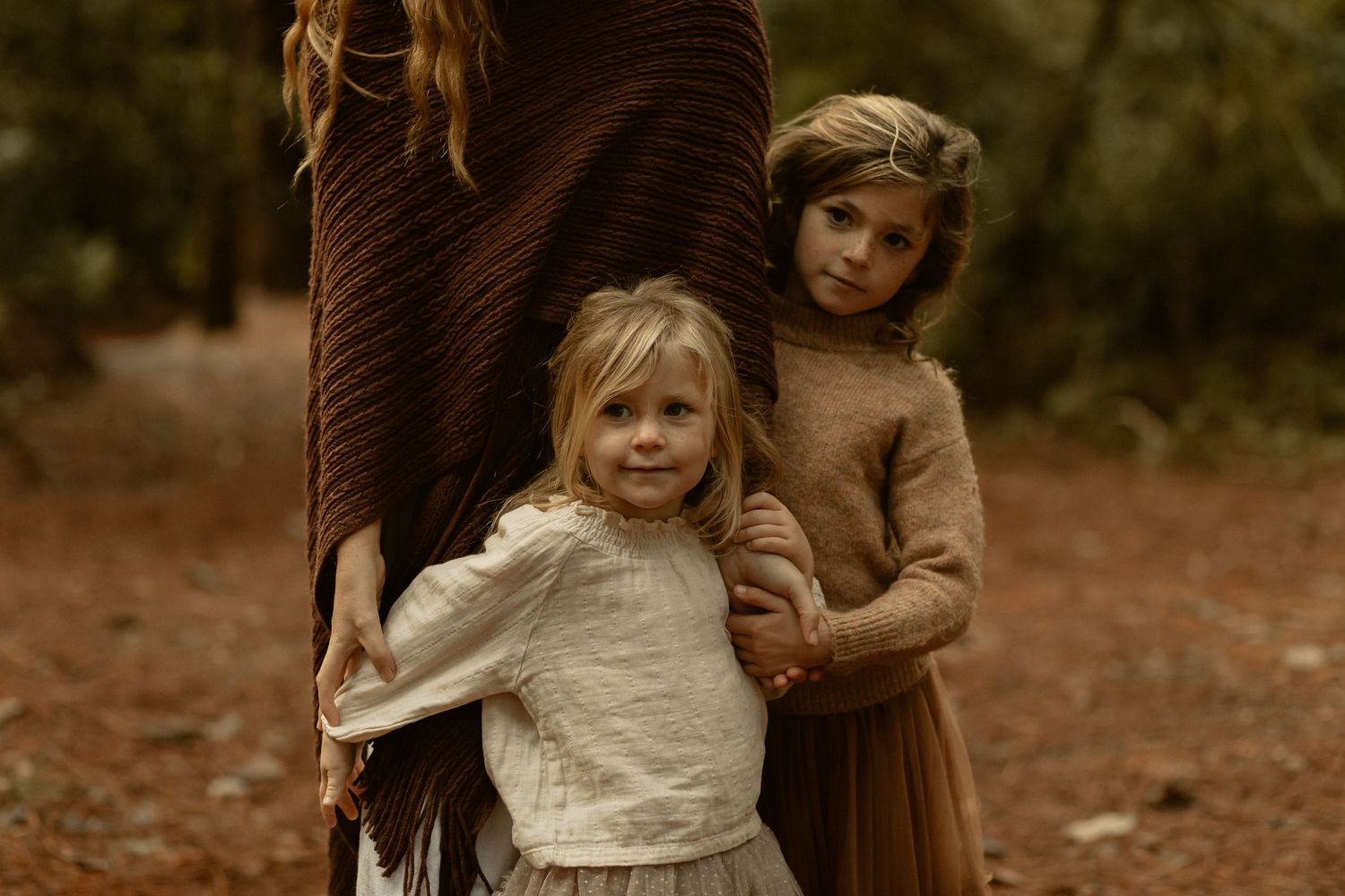 Tender family interaction captured in warm autumn light filtering through forest trees.