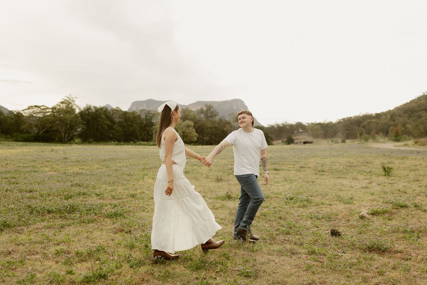 Romantic couple dances and twirls in an open field during golden hour.