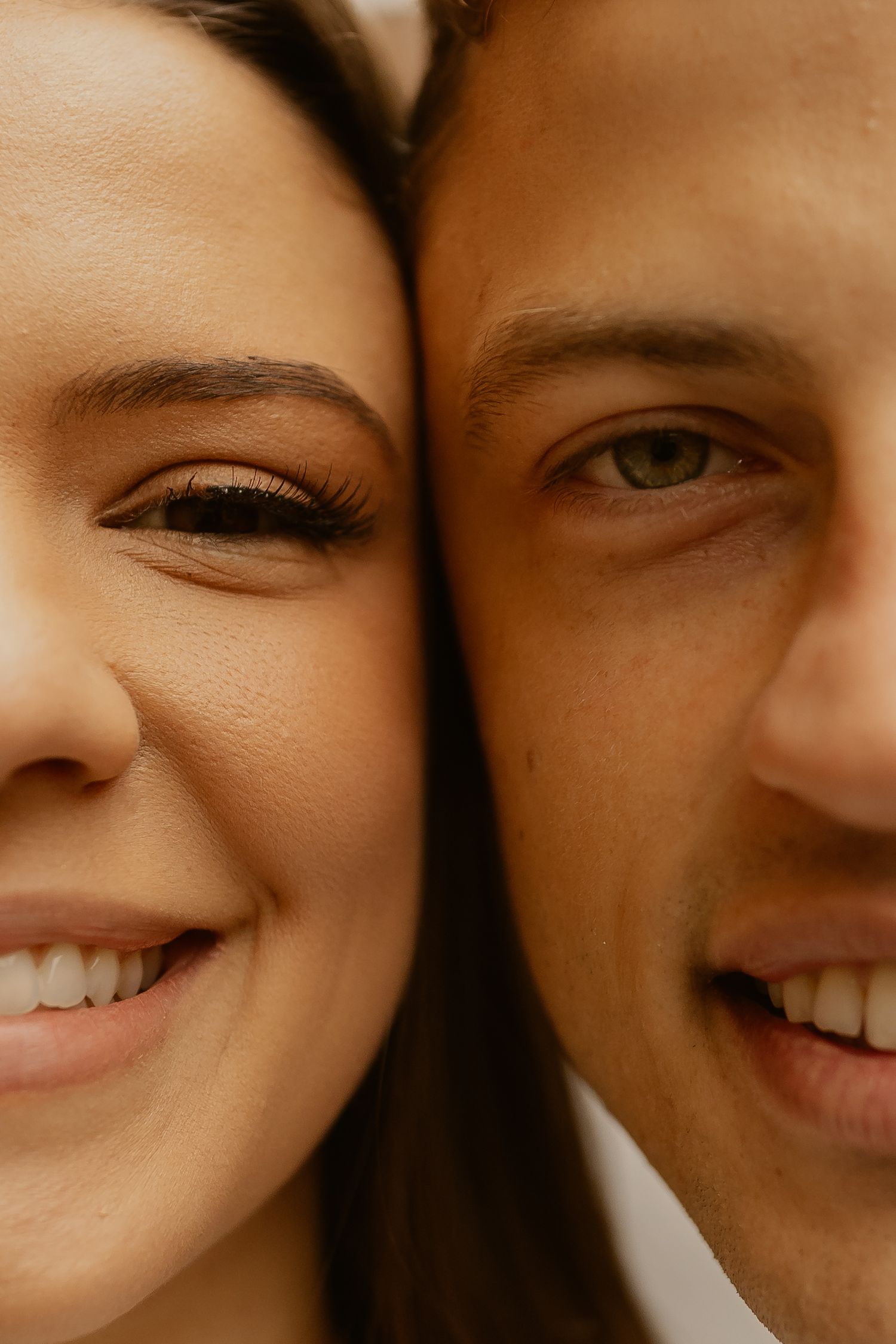 Close up portrait of couple smiling warmly in warm sepia tones.