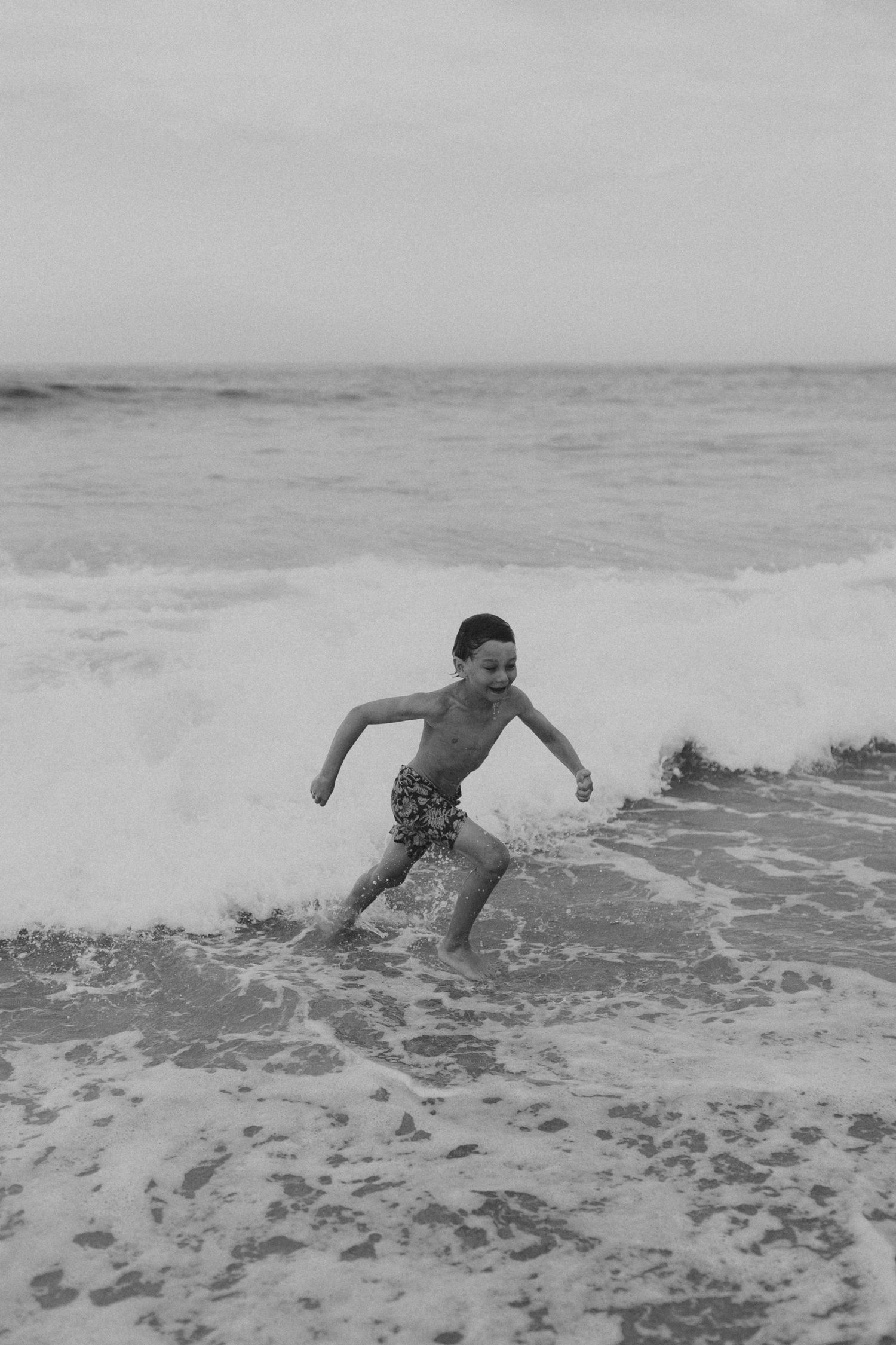 A sequence of black and white photos showing someone diving into ocean waves at the beach.