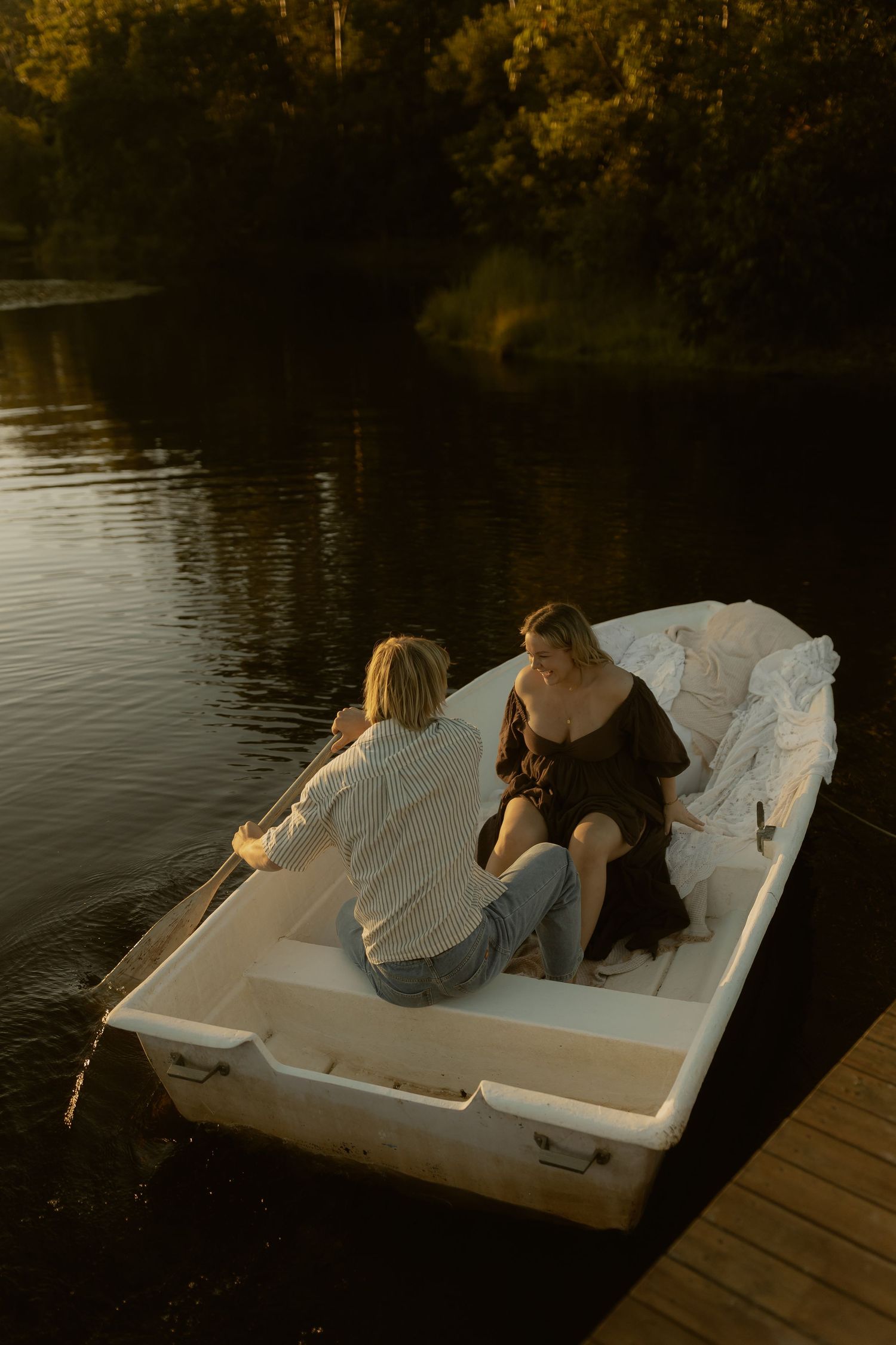 Two people relax on a white pedal boat at dusk on a peaceful lake.
