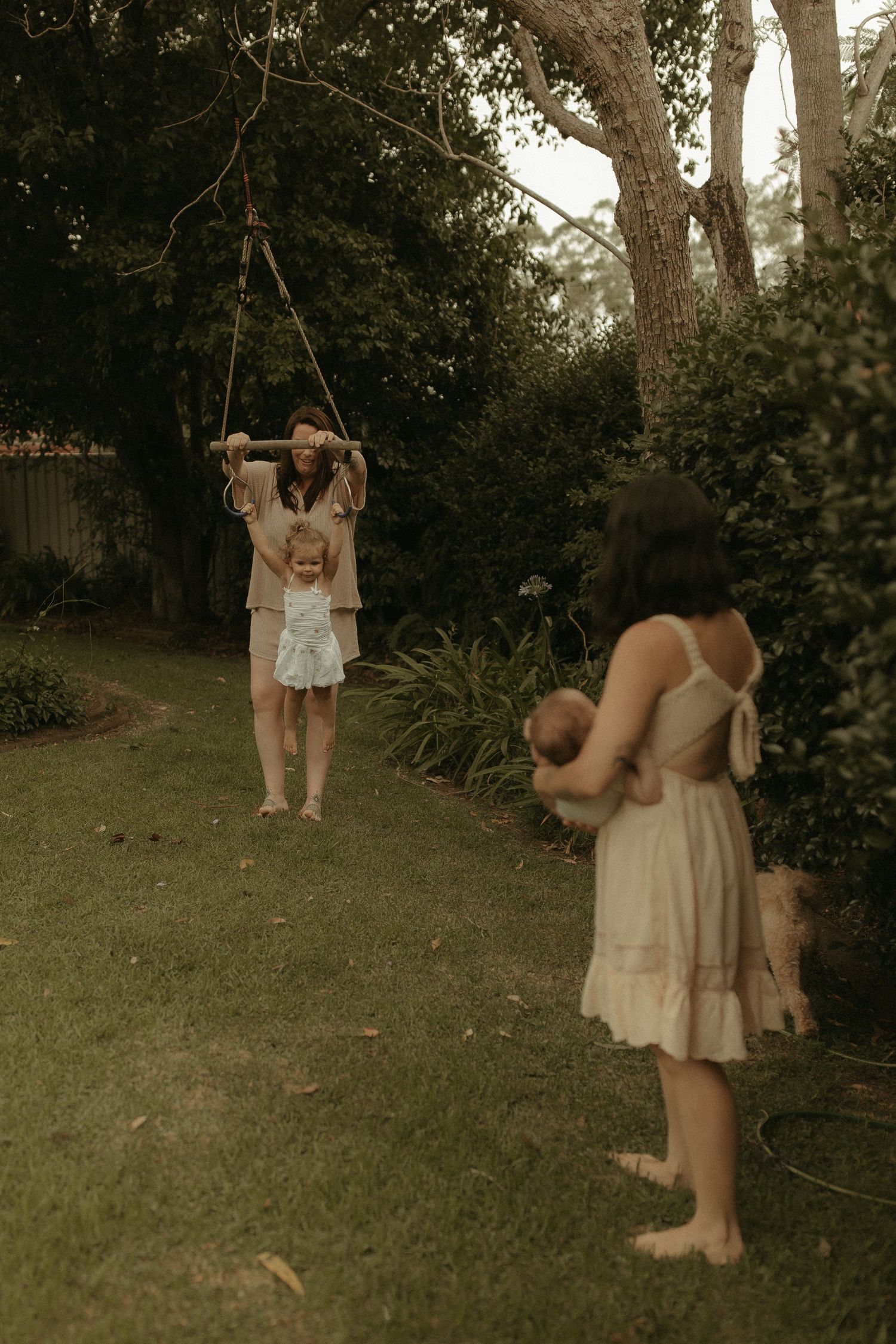 A series of photos showing people in light-colored dresses playing on a tree swing in a backyard garden setting.