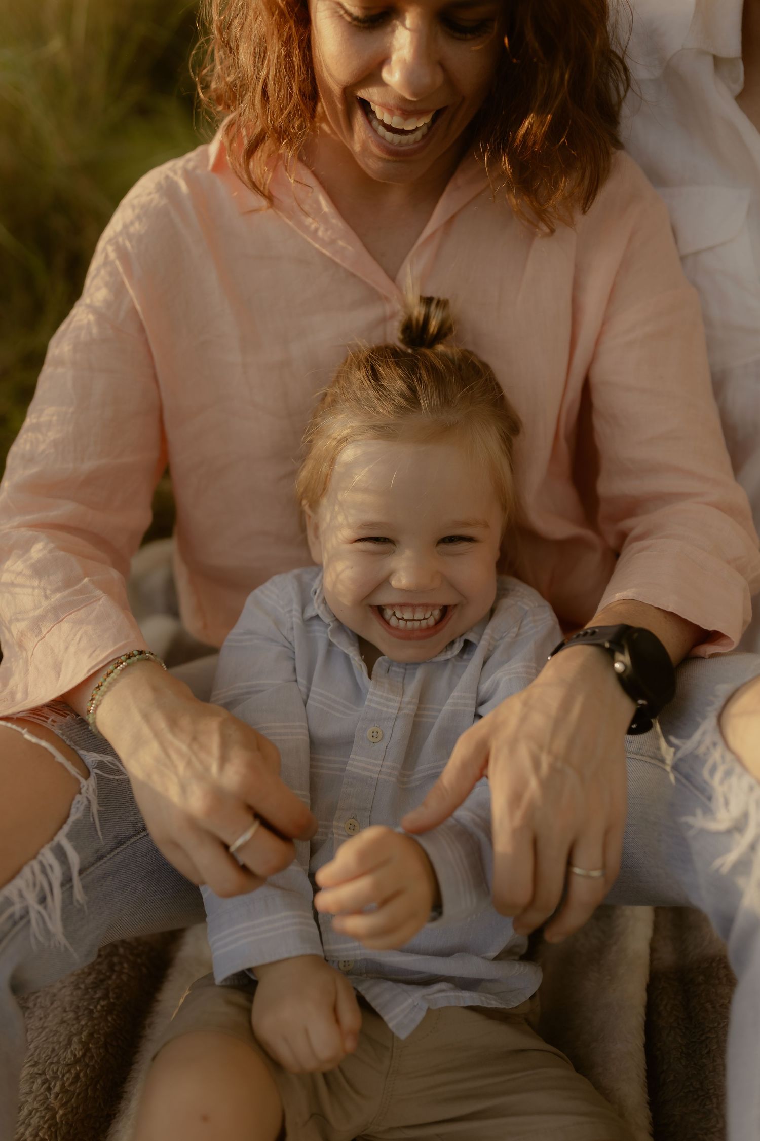 Candid family moments captured in warm lighting with genuine laughter and embraces.