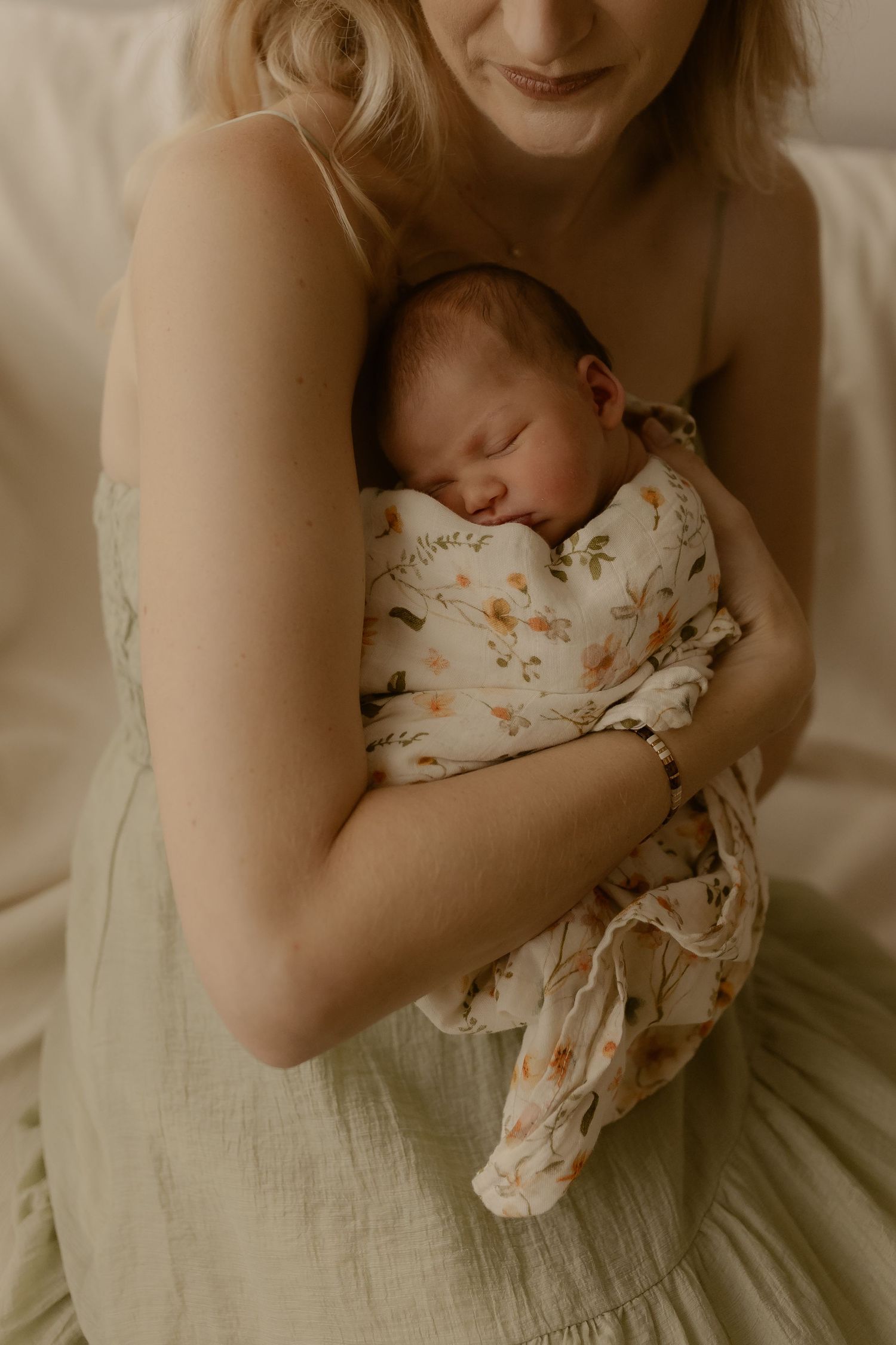 Tender moment with sleeping newborn wrapped in floral print.