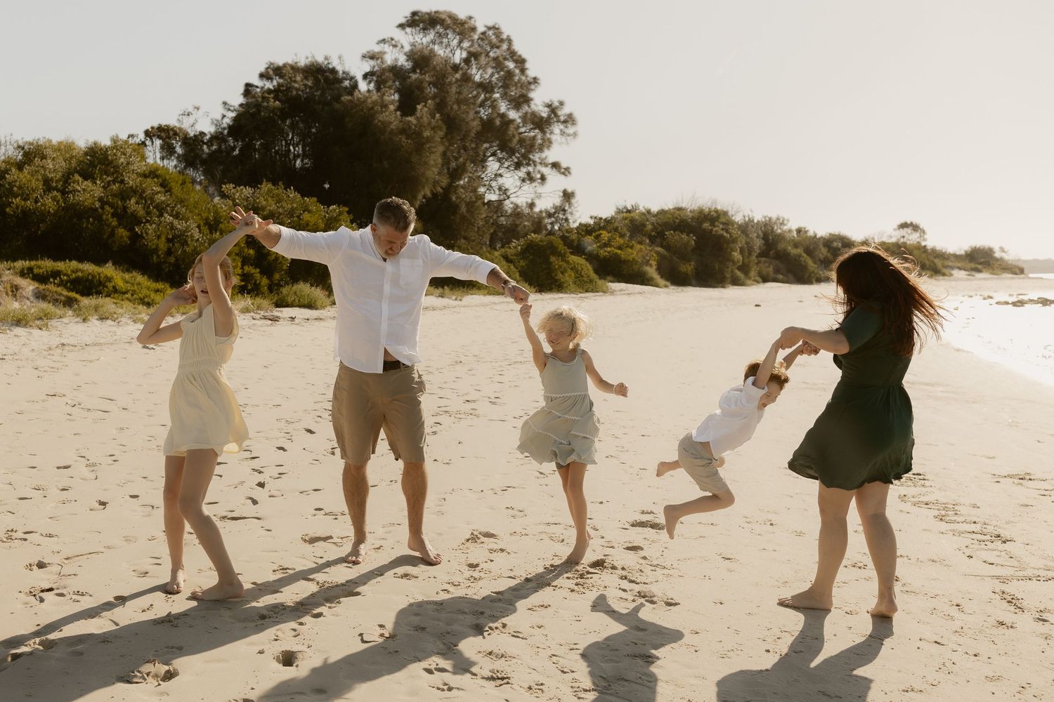 Action shots of a family playing and running together on a beach at sunset.