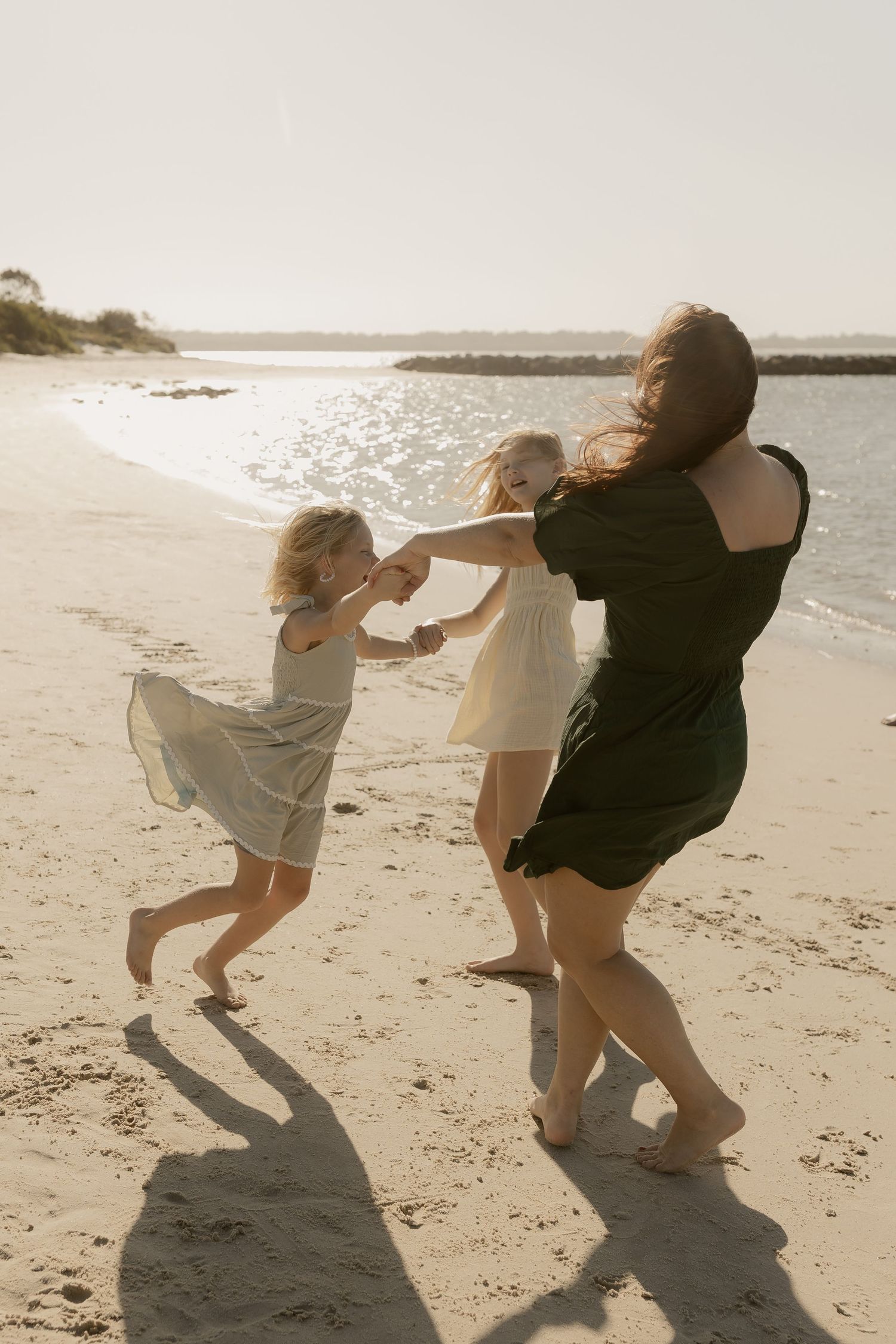 A playful sequence of dance moves on a sunlit beach with sparkling water in the distance.