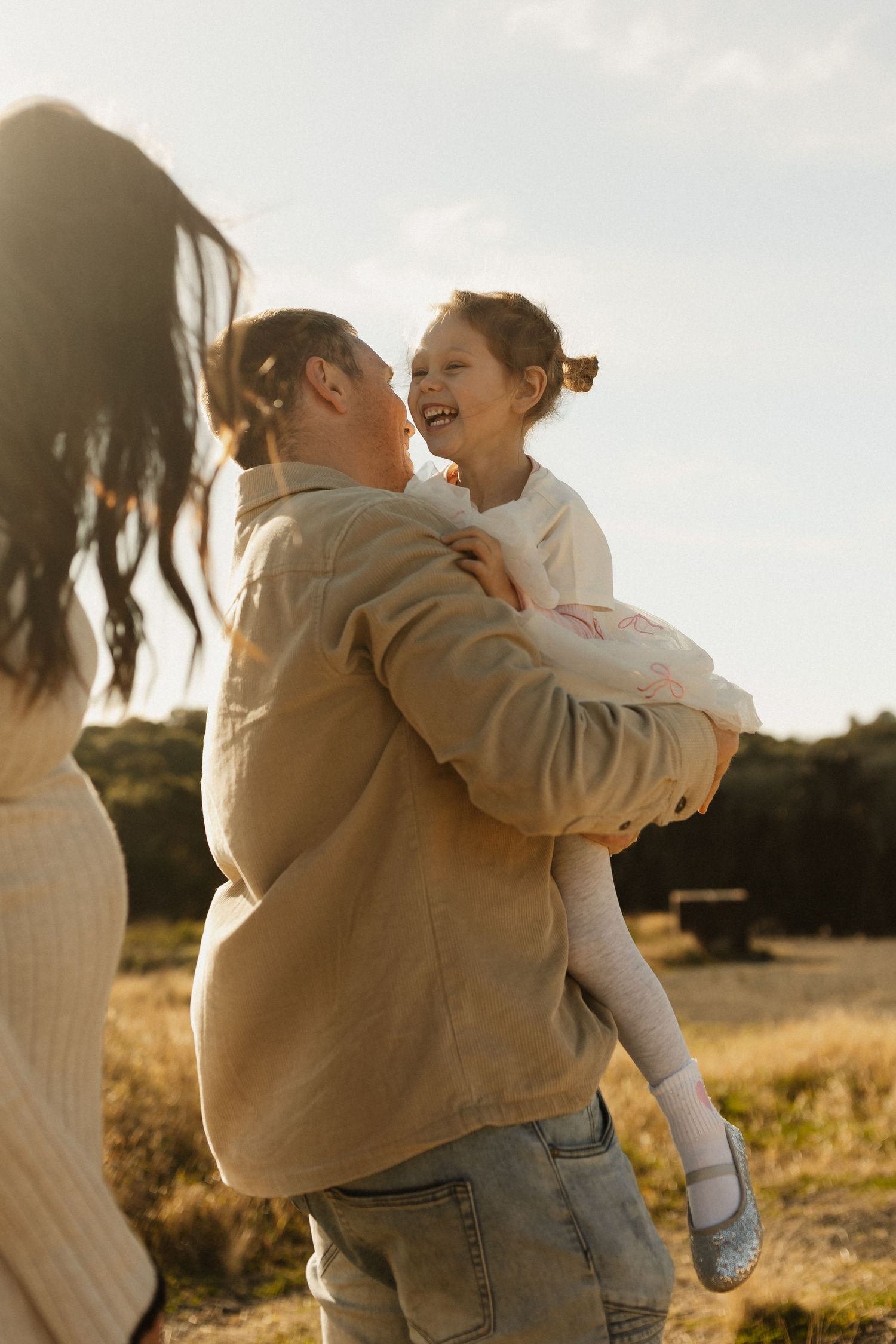 Candid outdoor family moment showing expressions of pure joy and laughter in warm sunset lighting.