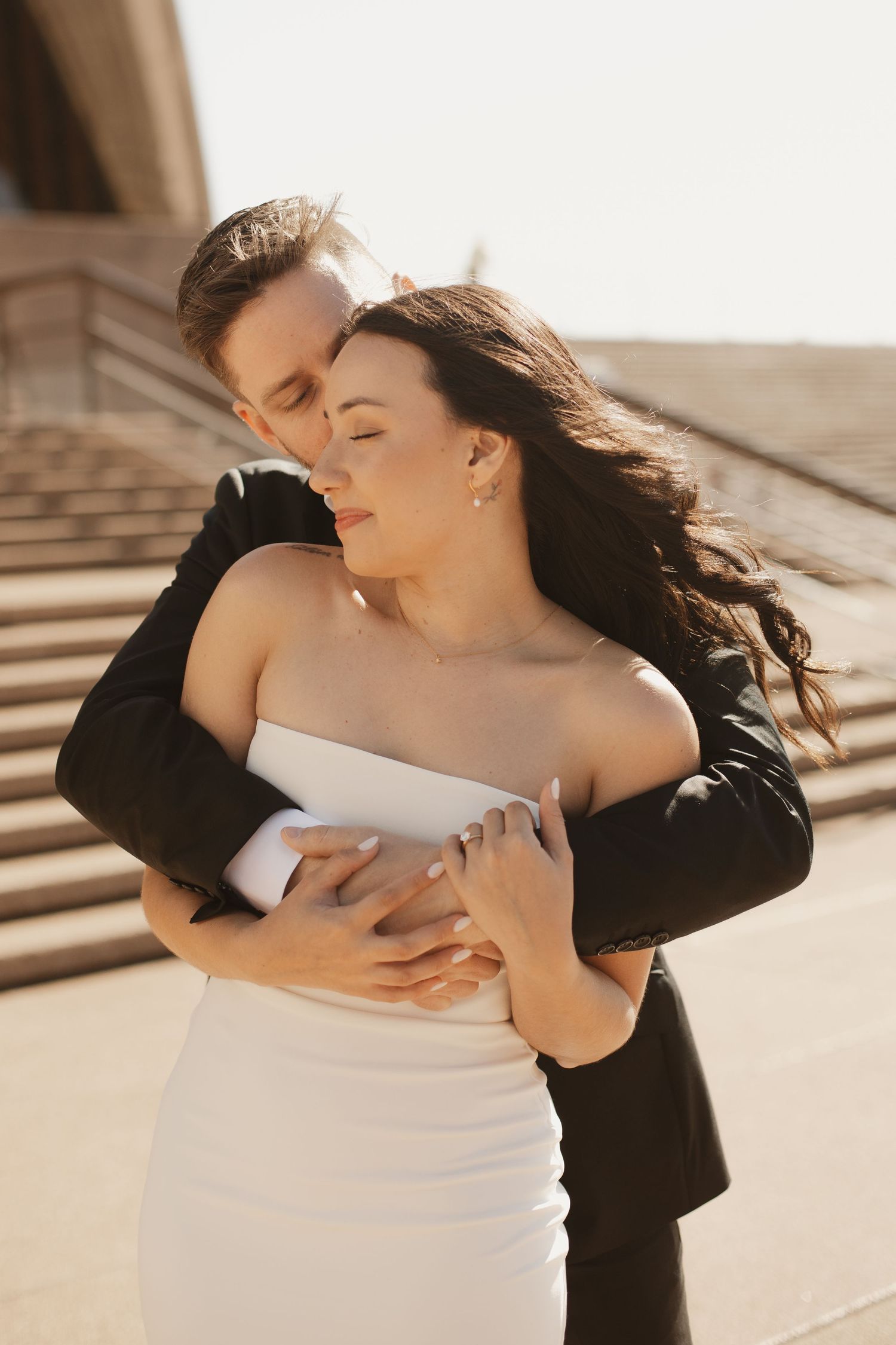 Intimate wedding moment captured in warm sunlight on stone steps.