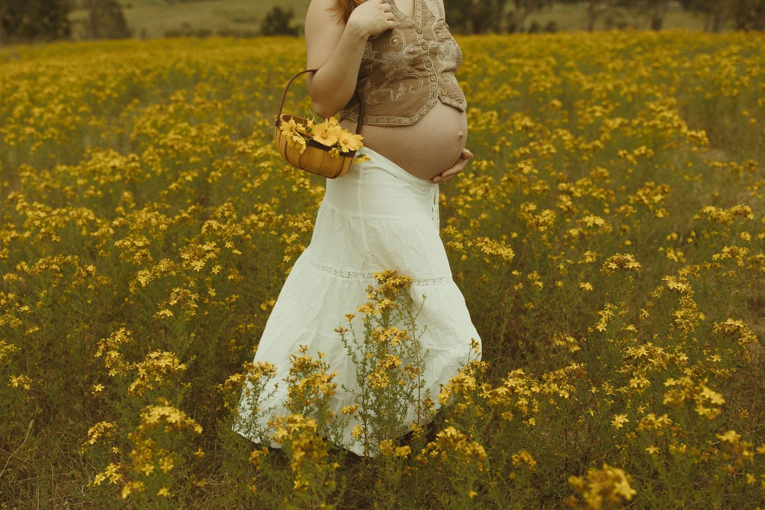 A figure in a white dress twirls through a vibrant field of yellow wildflowers on a sunny afternoon.