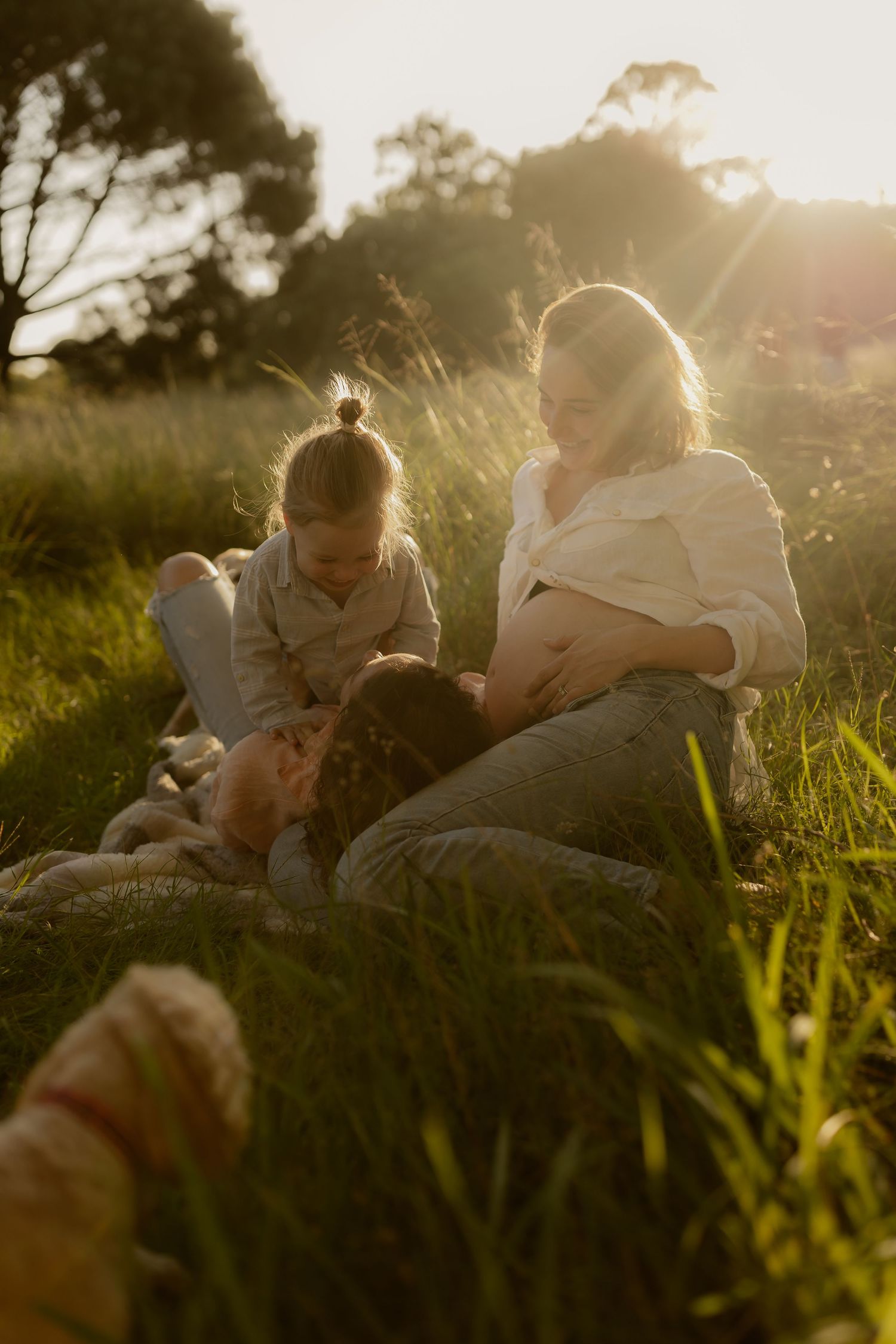 Intimate outdoor photoshoot with couple laying in tall grass during golden hour.