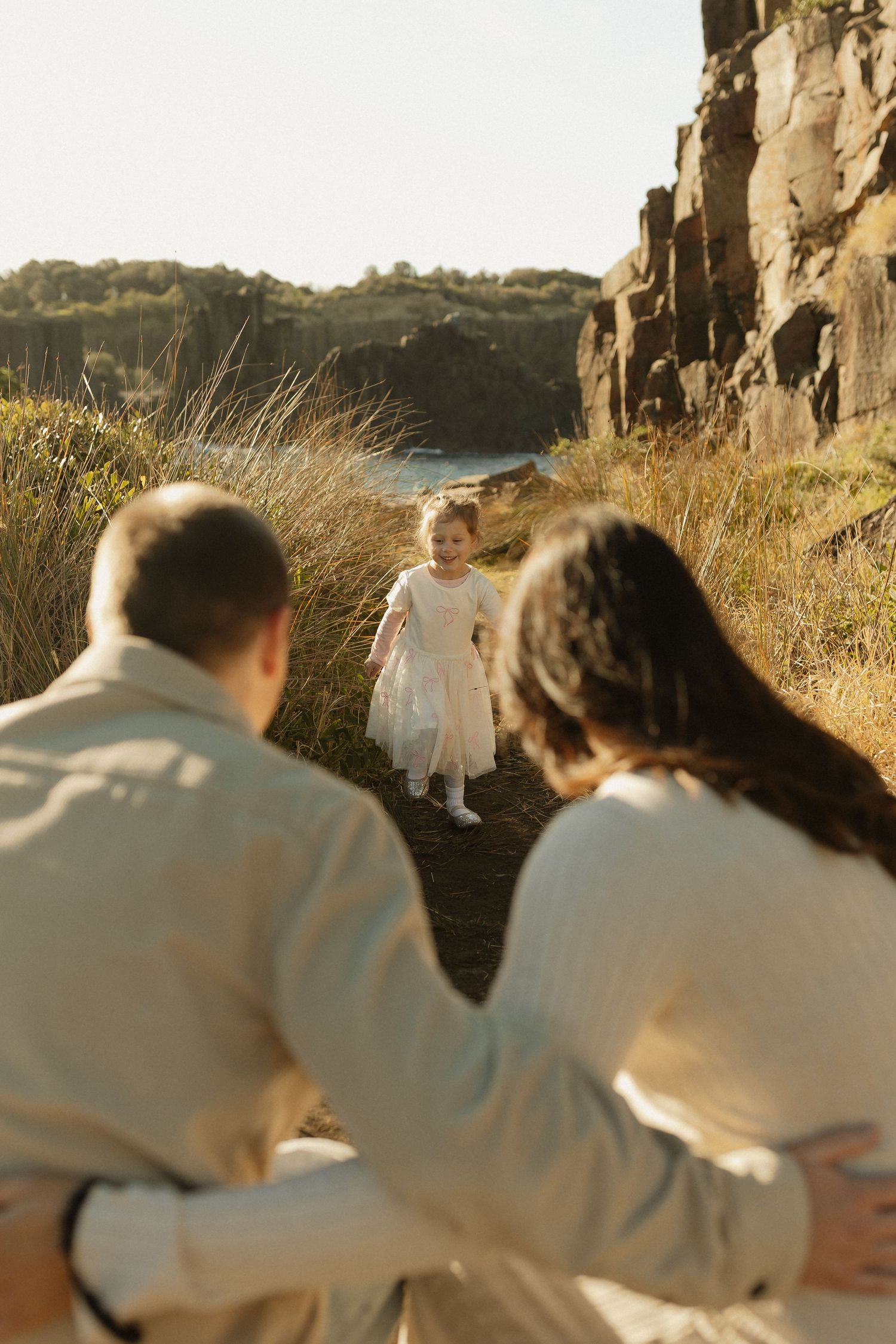Scenic outdoor family photo session with rocky cliffs and natural landscape in golden hour lighting.