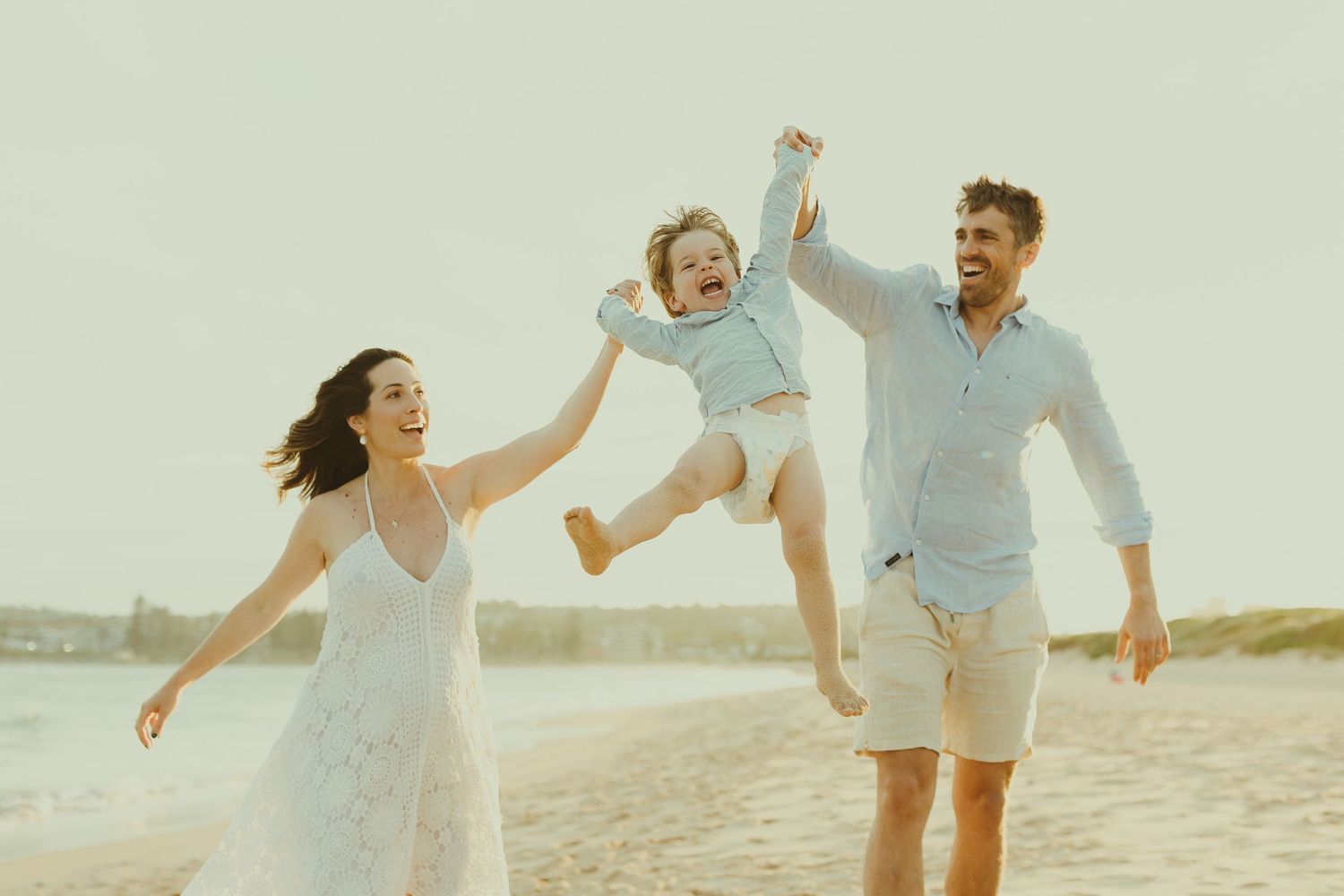 Energetic family running and playing together during beach photoshoot at sunset.