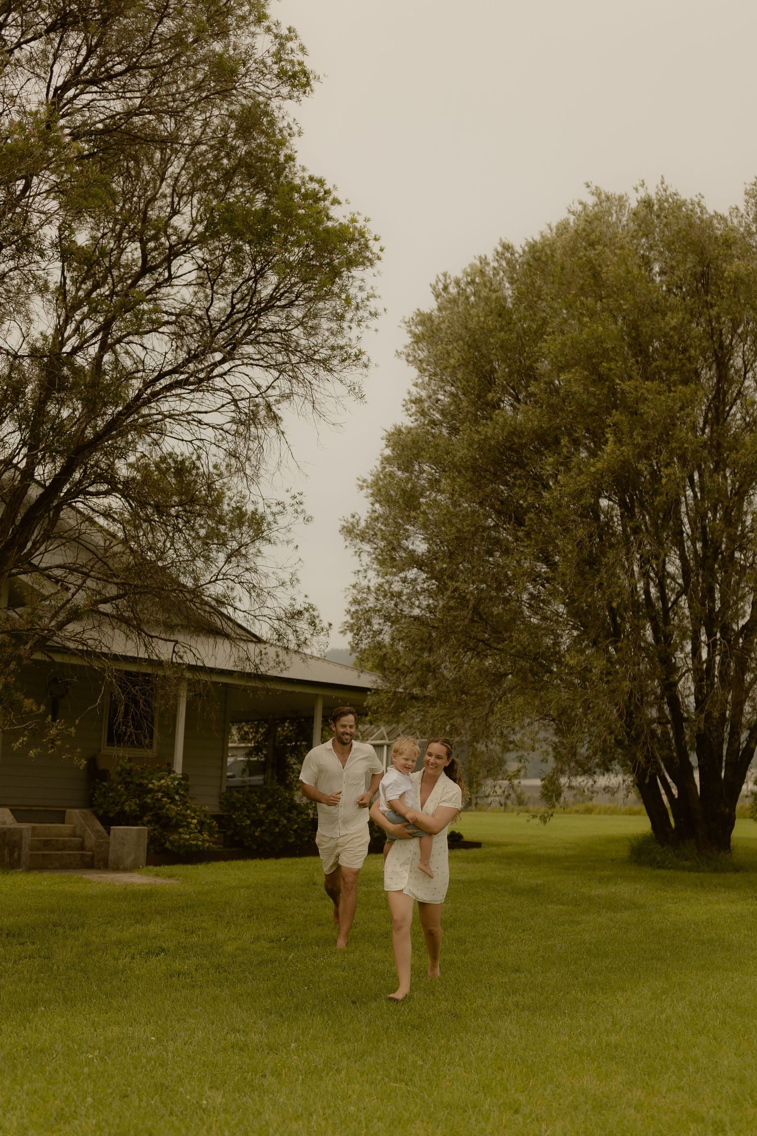People playing and running together in a green field with trees in the background.