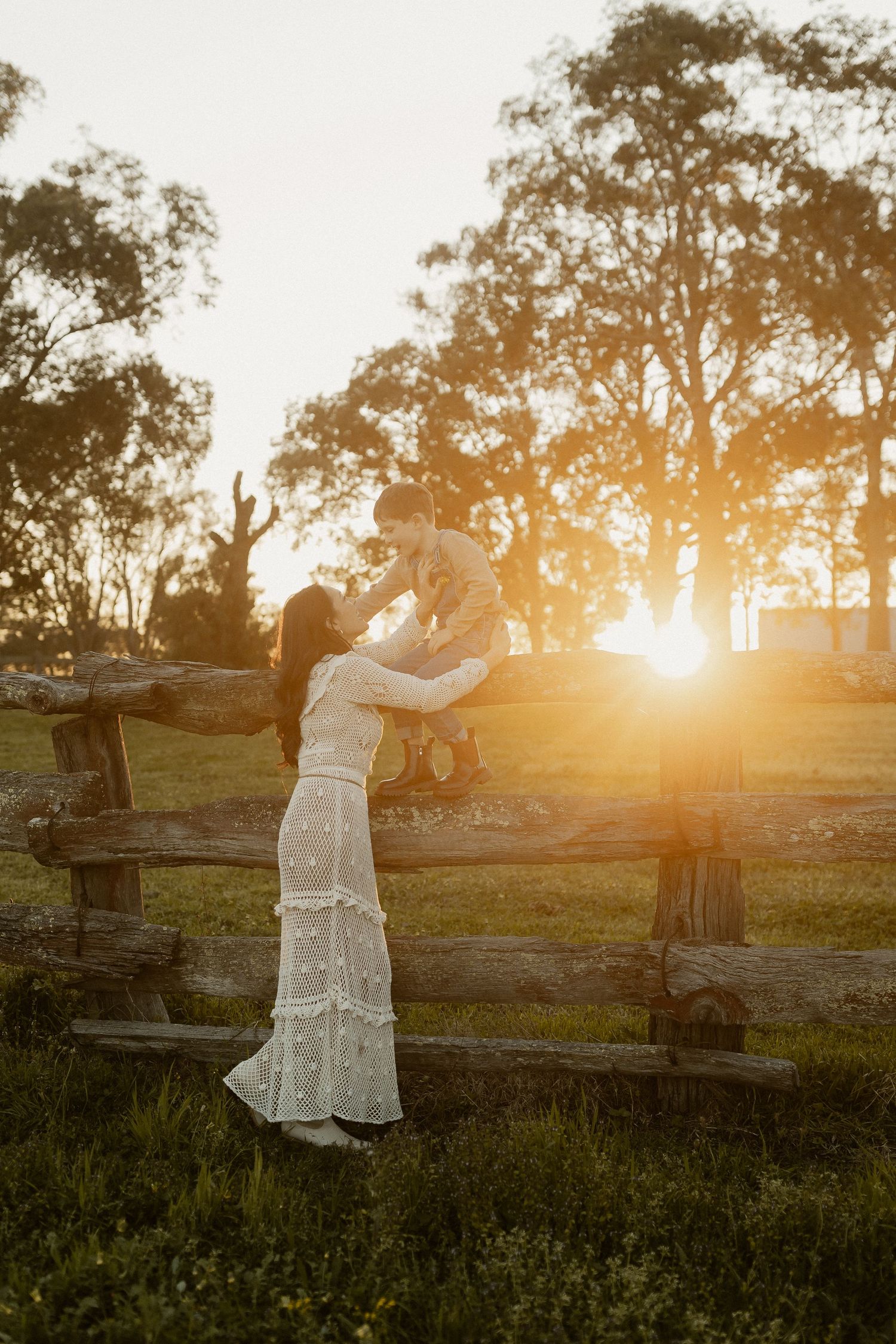 Romantic silhouettes of a couple standing in a meadow at sunset with trees in the background.