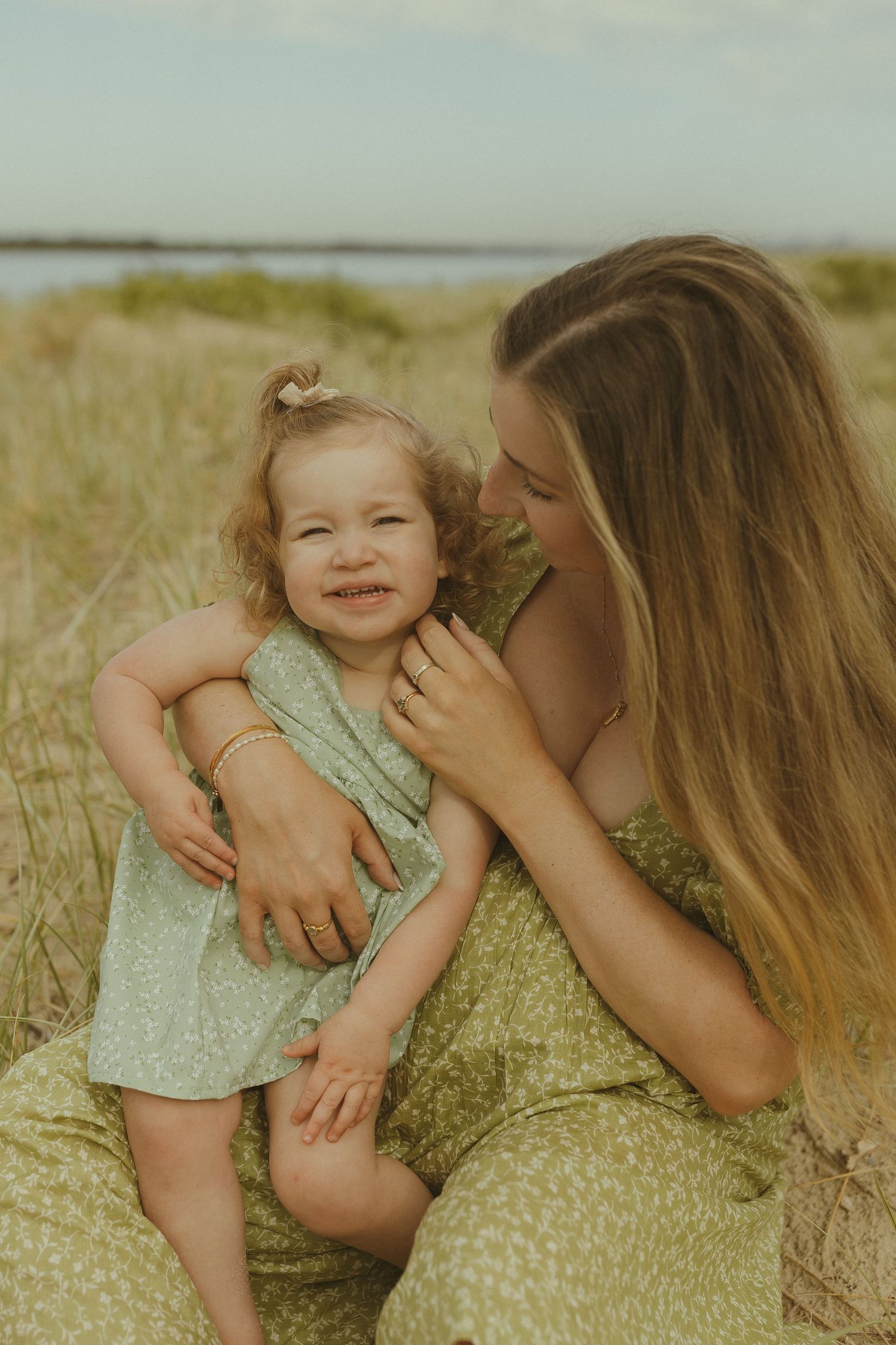 A tender moment captured in a grassy field with warm lighting and vintage tones.