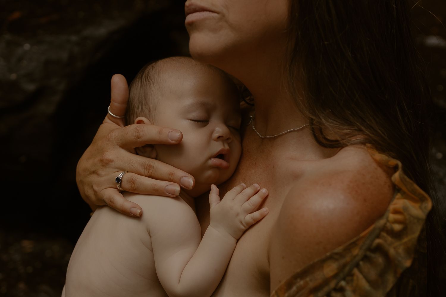 A tender moment between parent and newborn baby captured in warm, intimate lighting.