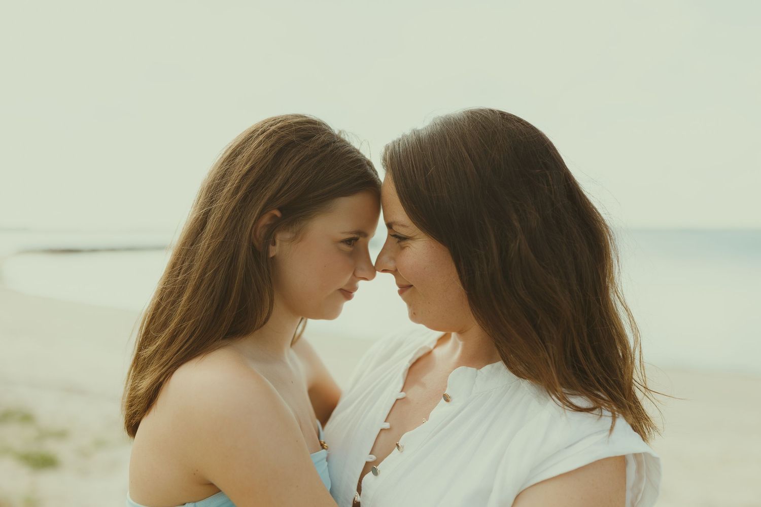 Two people share an intimate moment together at the beach during golden hour.