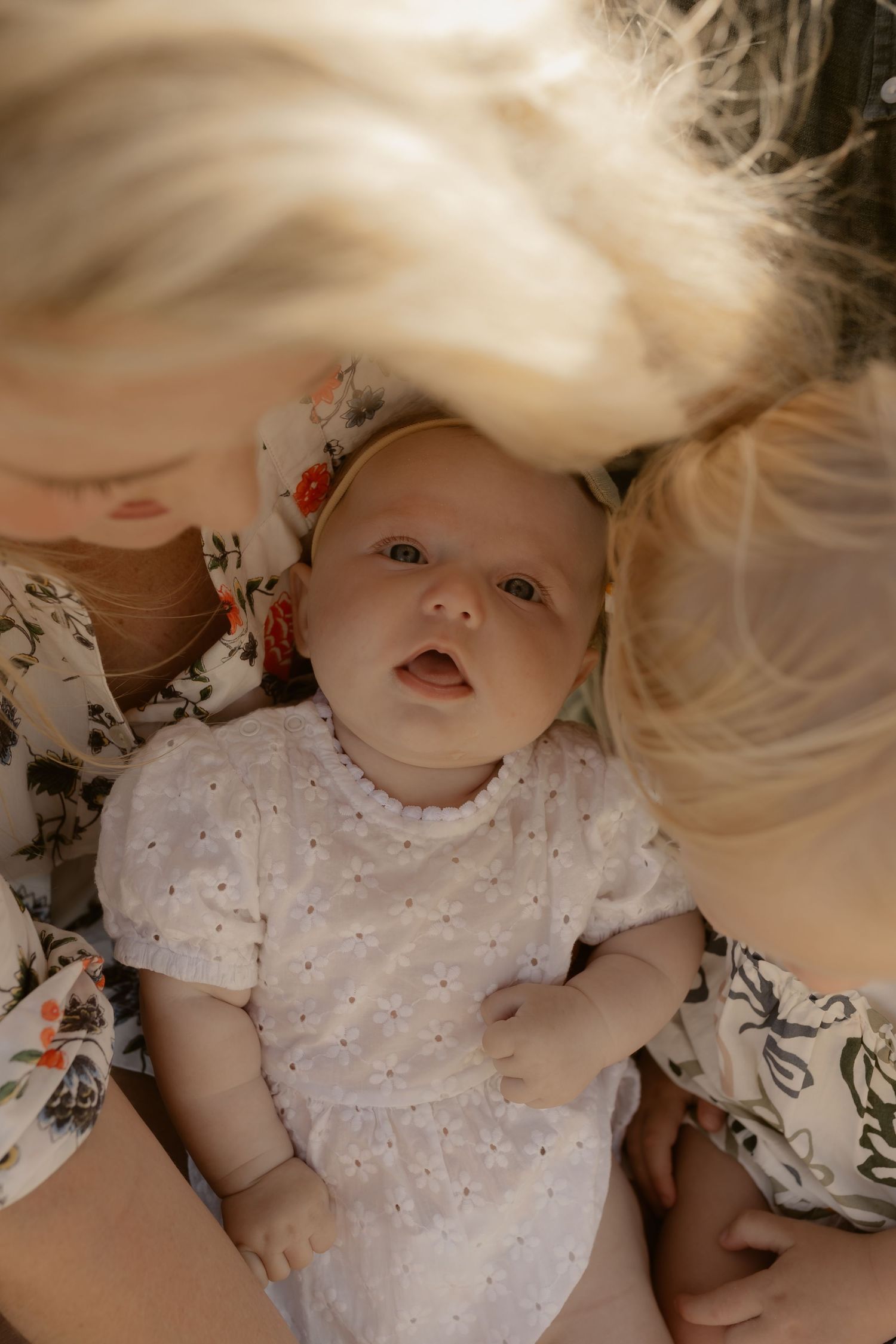 A baby in a white polka dot dress lying down with blonde hair flowing around them.