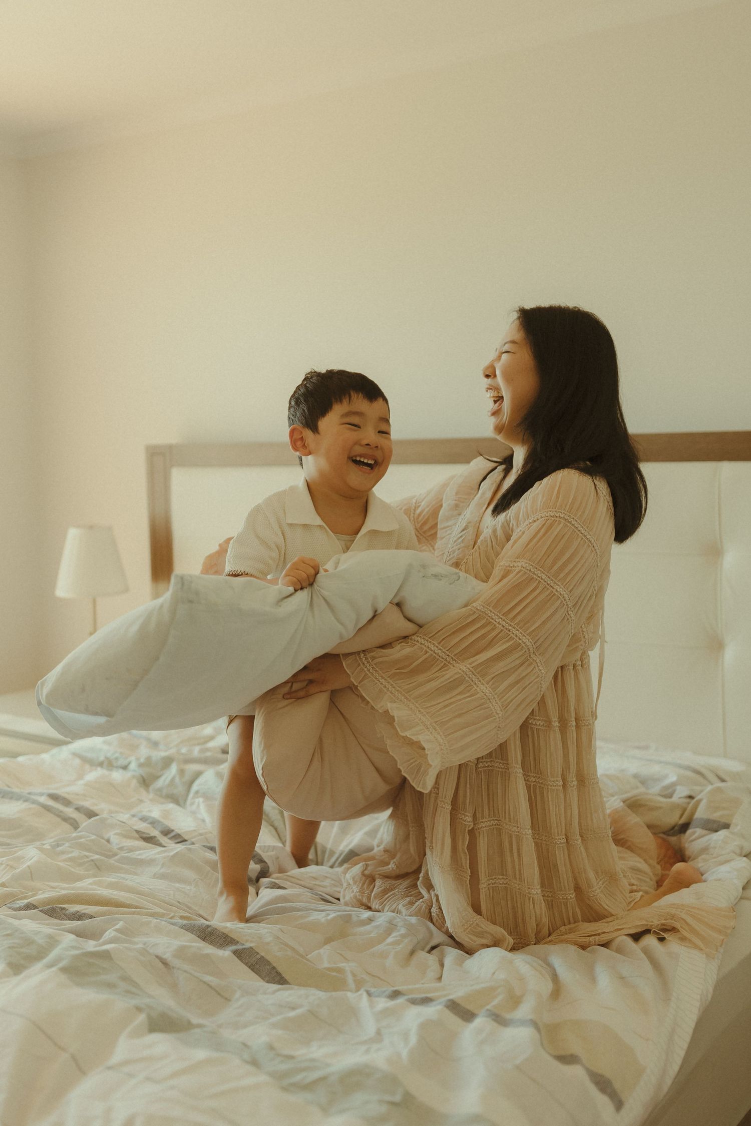 Playful pillow fight moments captured on a bright white bed.