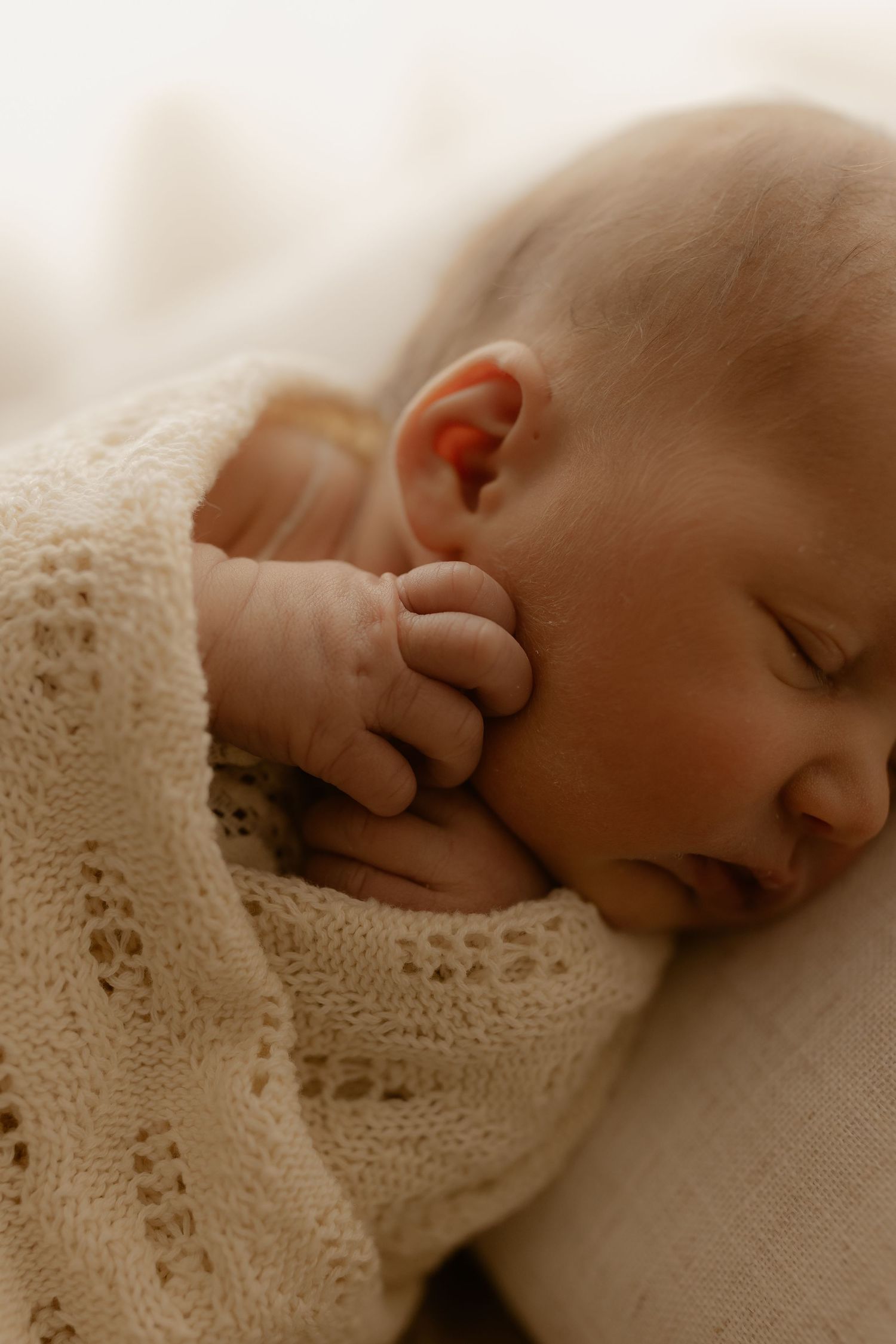 Sleeping newborn wrapped in delicate lace blanket.