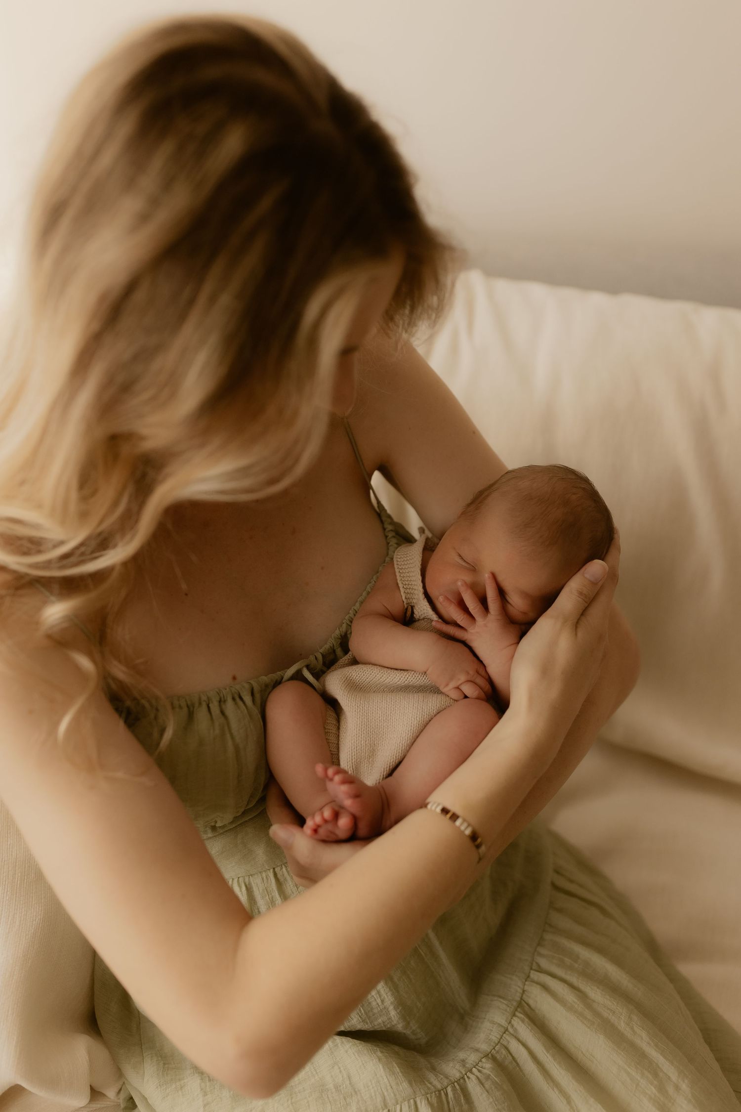 Tender moment of parent and newborn resting together on white bedding.
