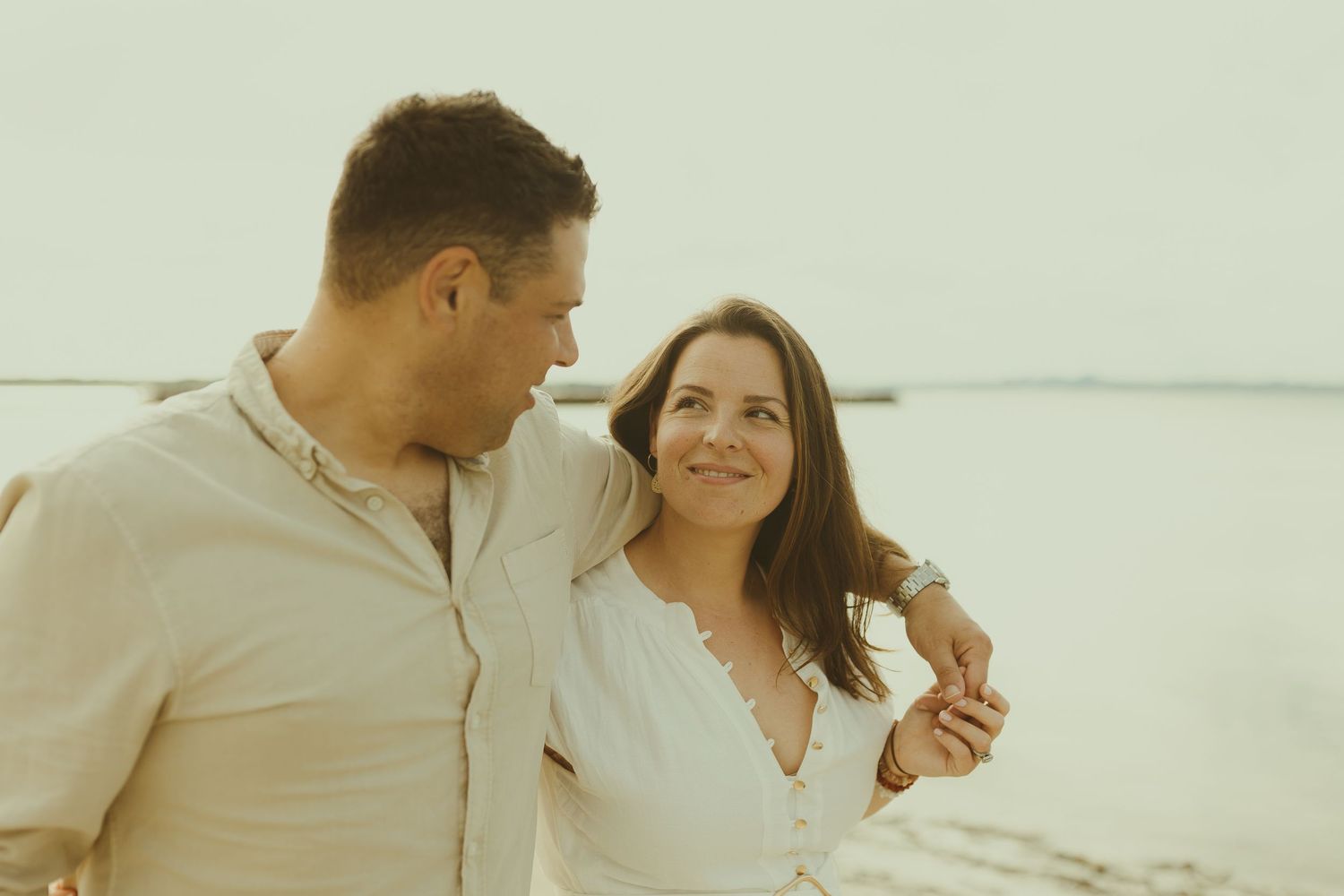 Couple sharing romantic moments while walking along a serene beach at sunset.