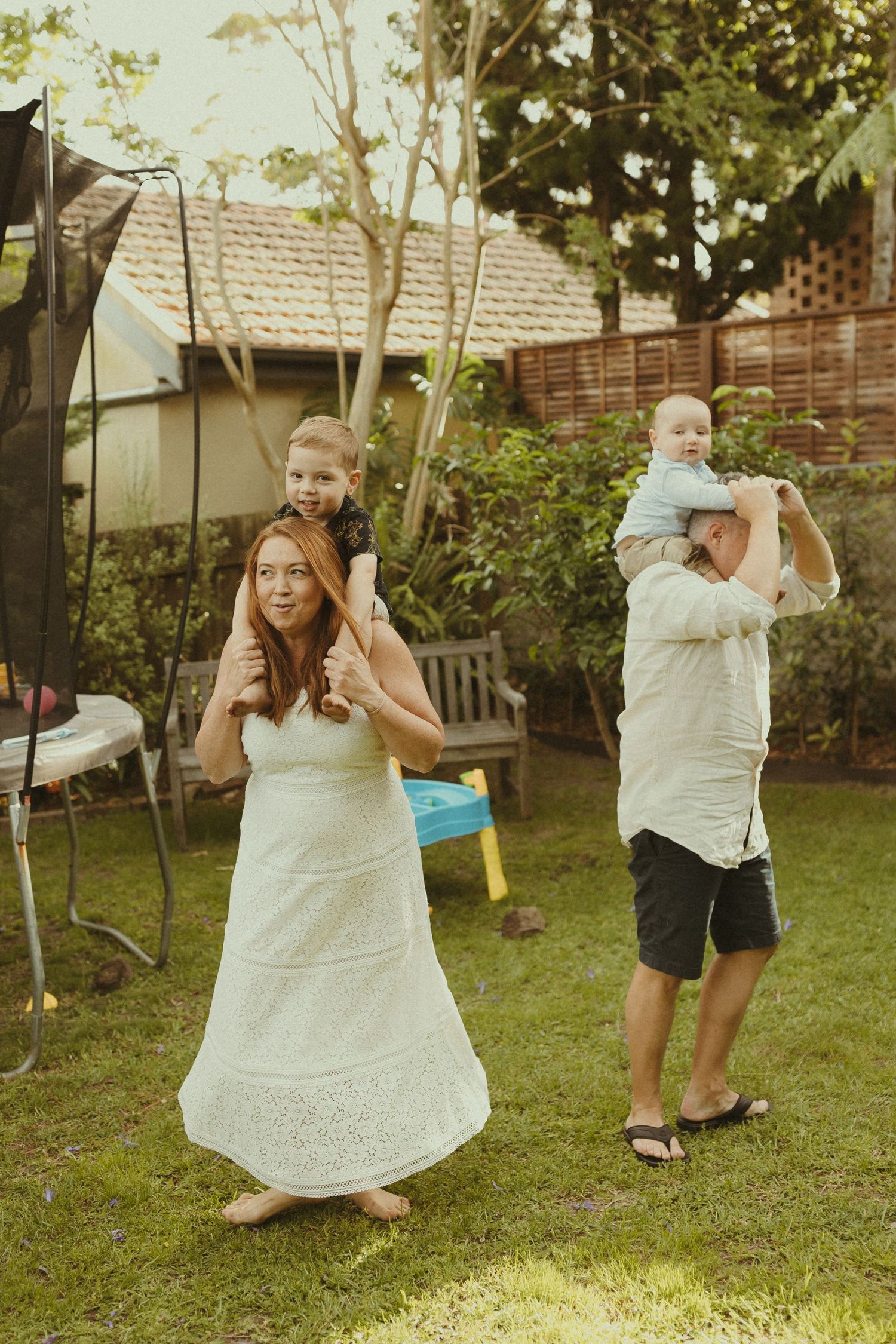 A joyful dance scene in a backyard with people in white dresses twirling in summer sunlight.