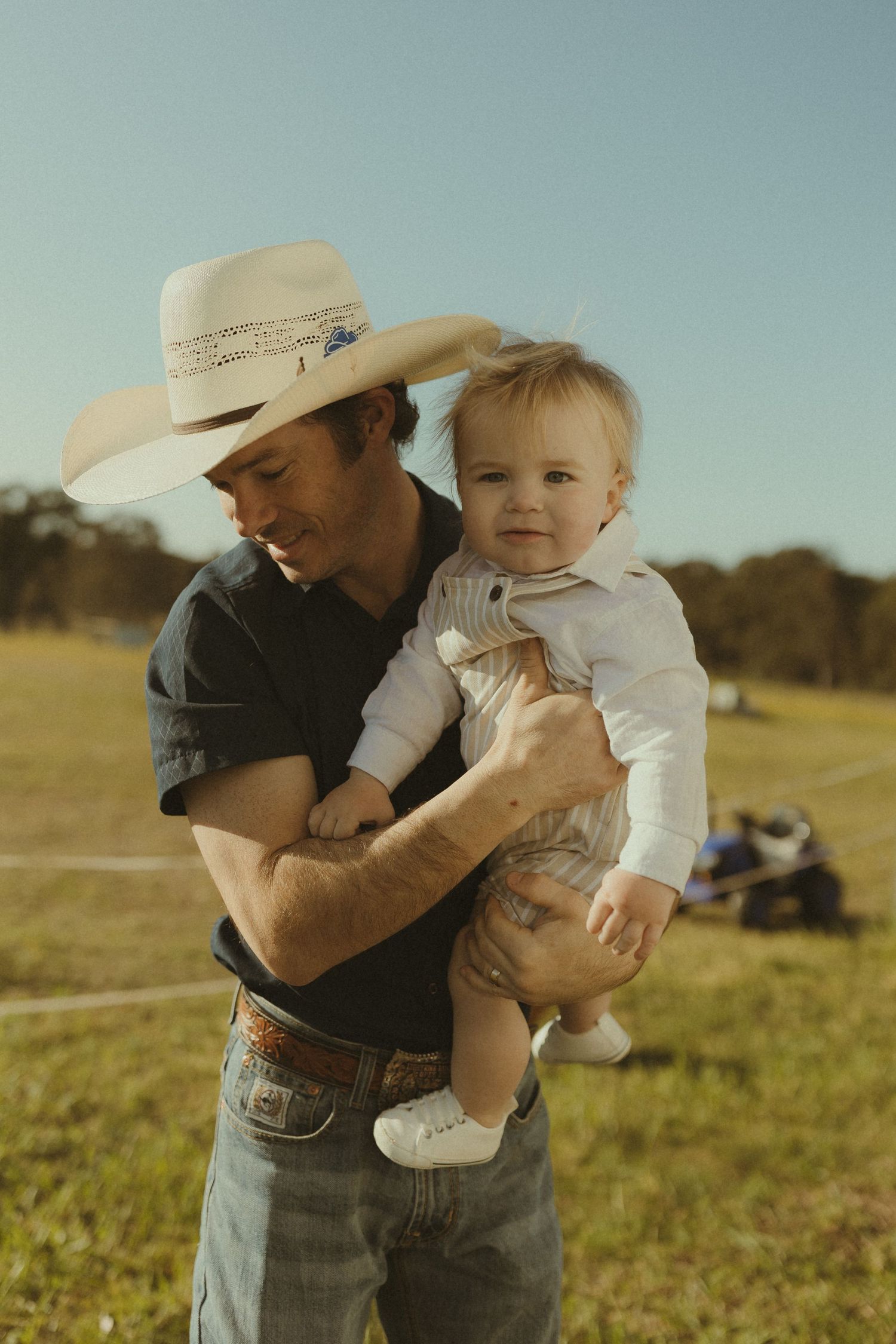 Candid moments between parent and child playing in a grassy countryside setting.