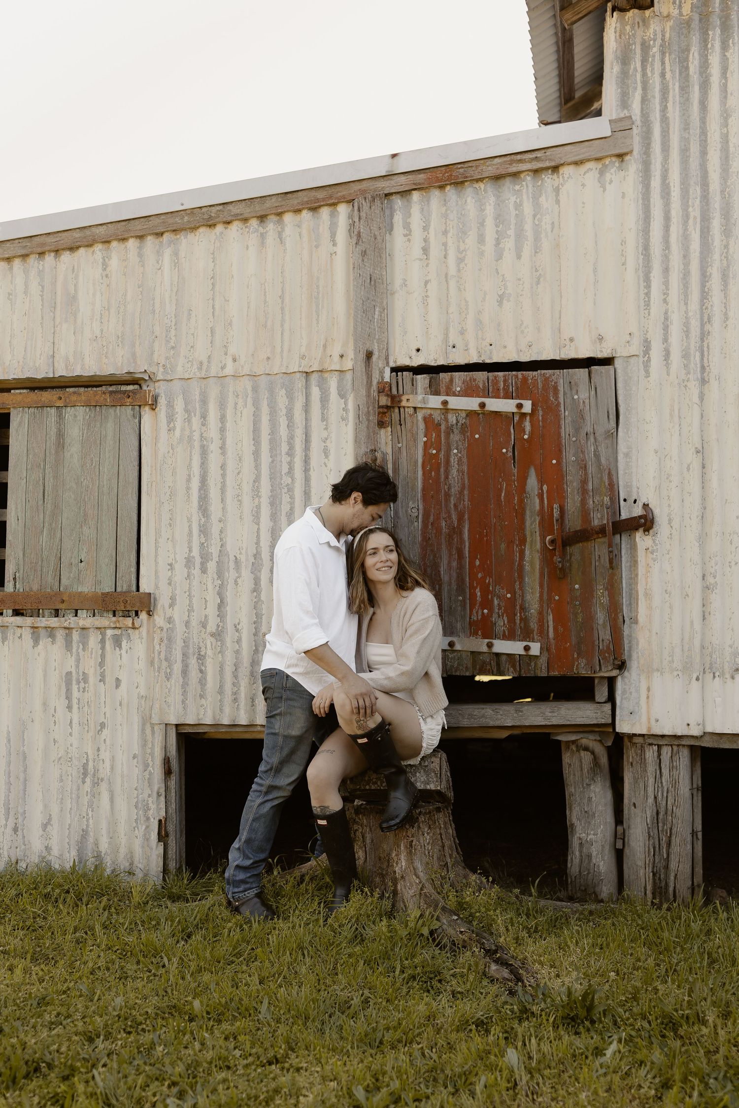 Playful sequence showing interaction by a rustic white barn with red doors.