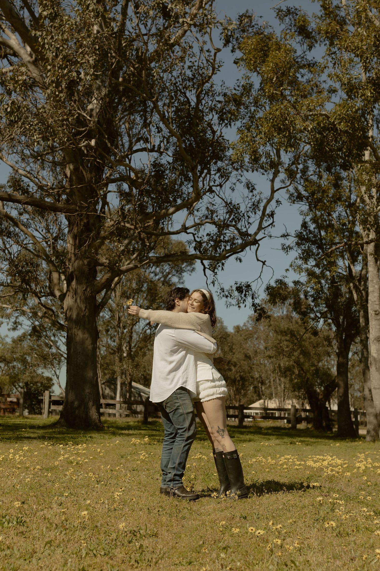 Romantic sequence of two people sharing intimate moments near a large tree in a grassy field.