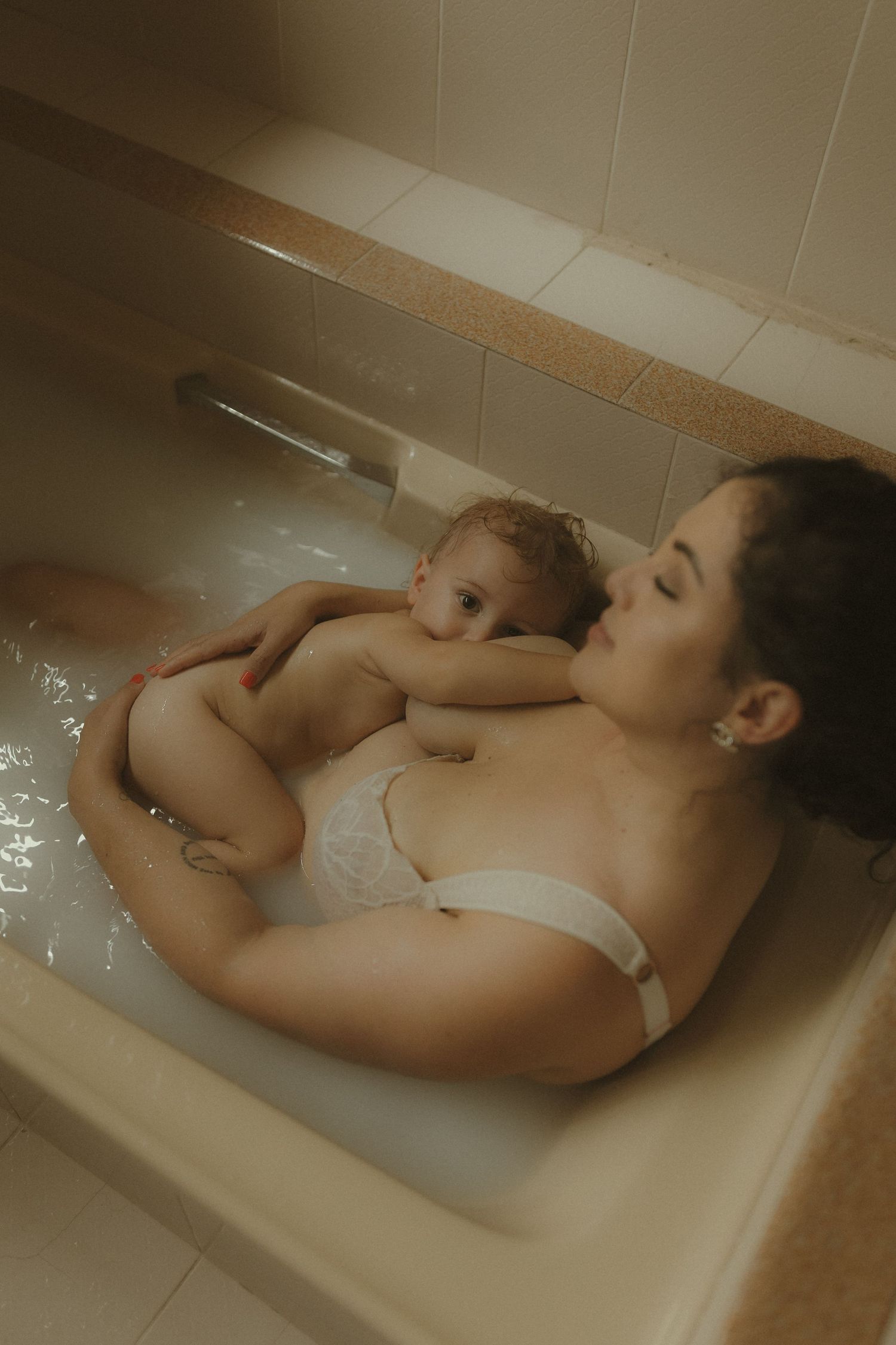 Artistic bathtub portrait captures peaceful relaxation between parent and child in muted tones.