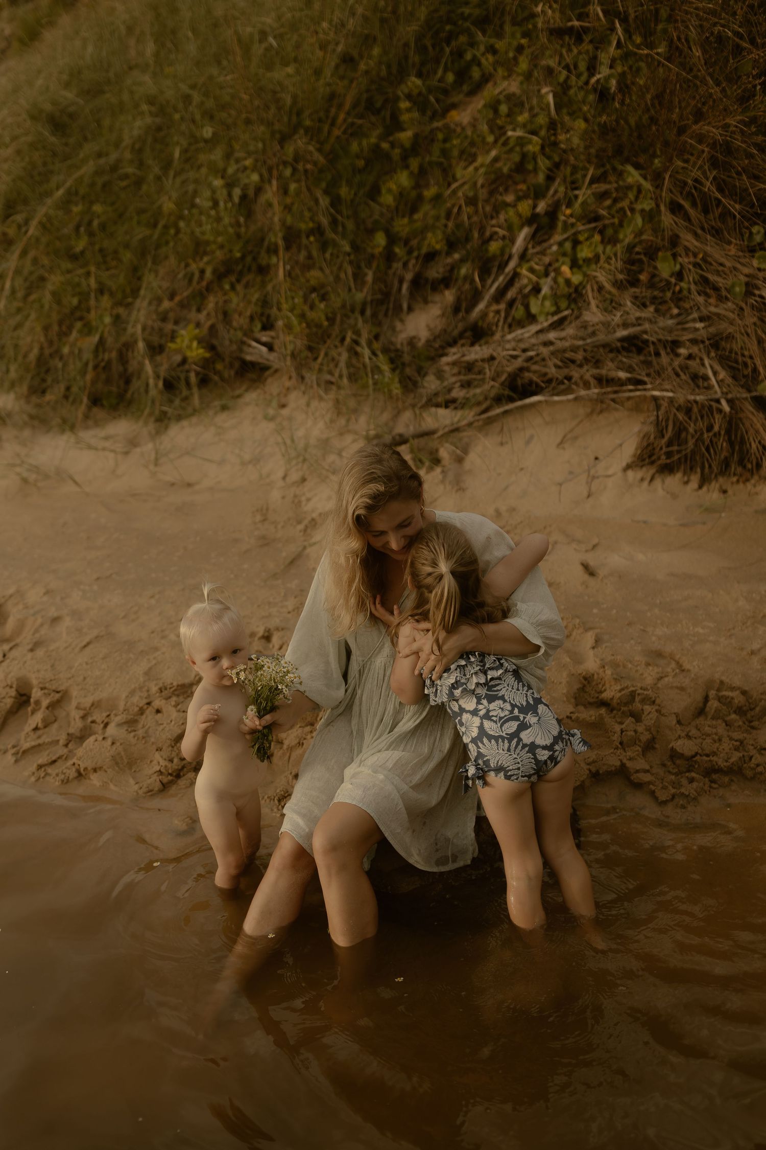 A series of sepia-toned photos showing people lying on a sandy beach near grass.