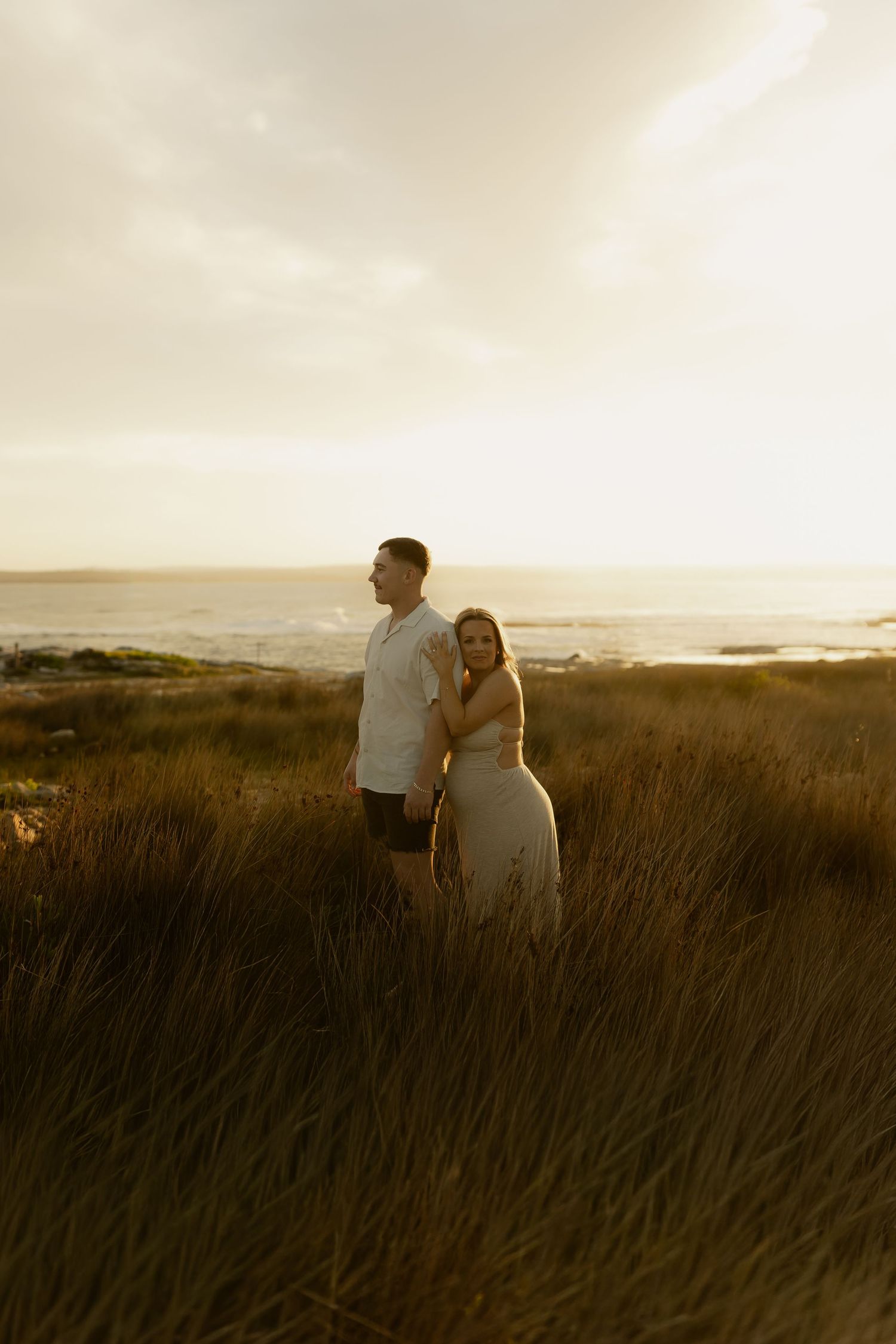 Silhouettes of people standing in tall grass during golden hour with a dreamy sunset backdrop.