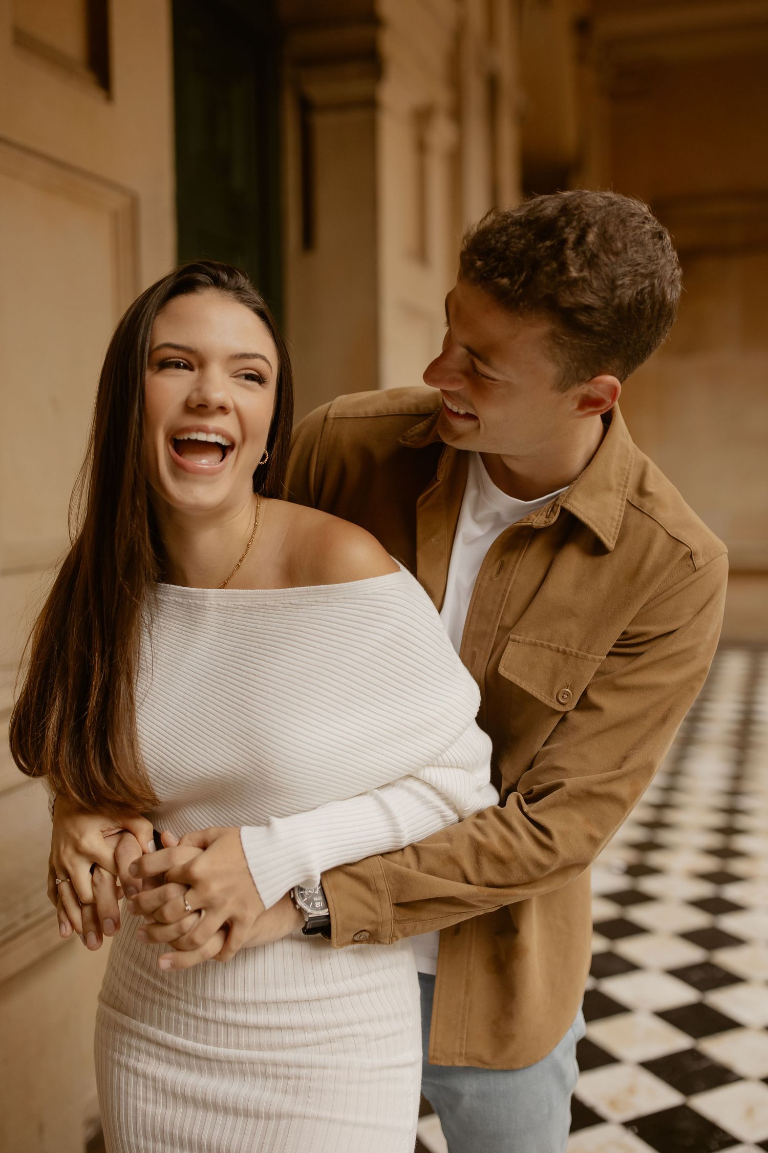 Happy young couple sharing a joyful moment together in an elegant hallway with checkered floor.