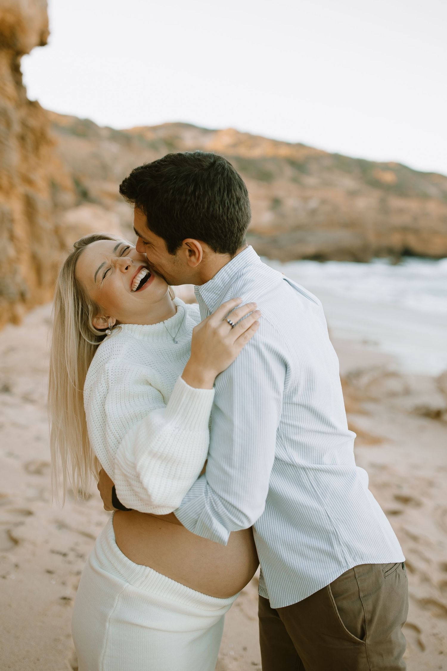 A tender moment captured between a couple during their beachside maternity photoshoot at sunset.