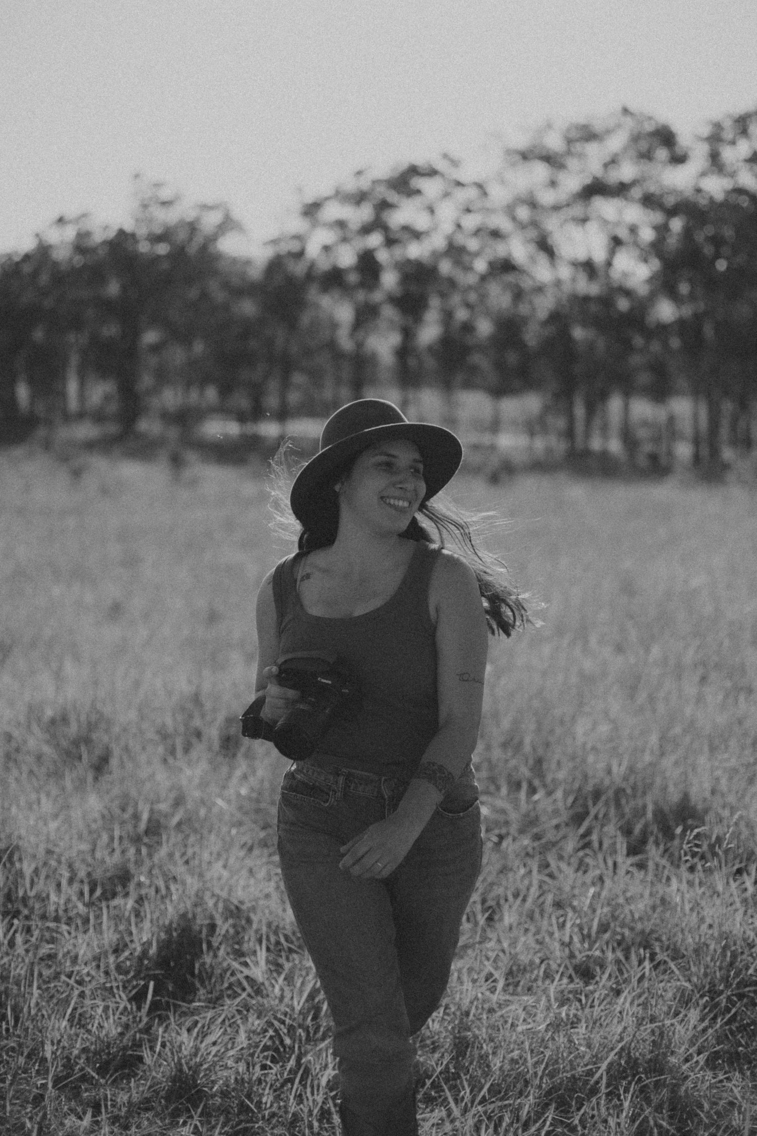 A series of black and white photos showing someone bending down in a grassy field with trees in the background.