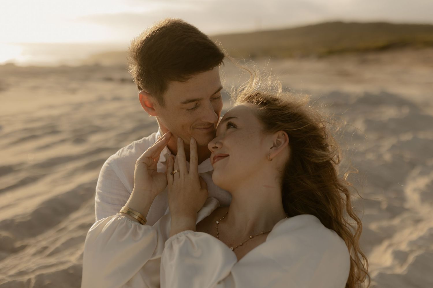 Romantic couple sharing tender moments on a sandy beach at sunset in a series of connected photographs.