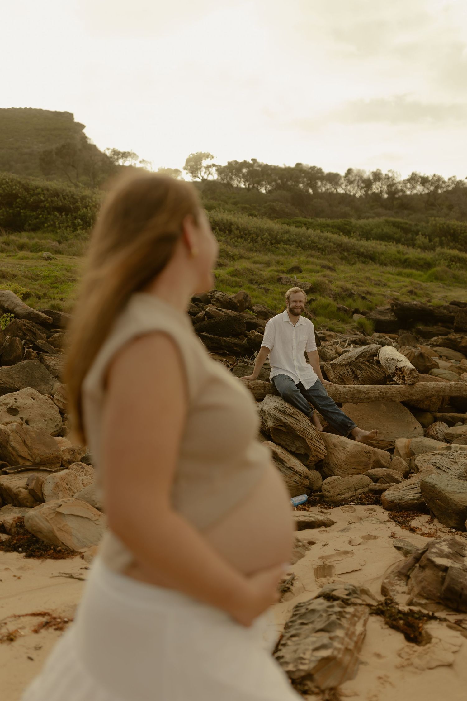 Couple sharing tender moments among coastal rocks during a beach photoshoot.