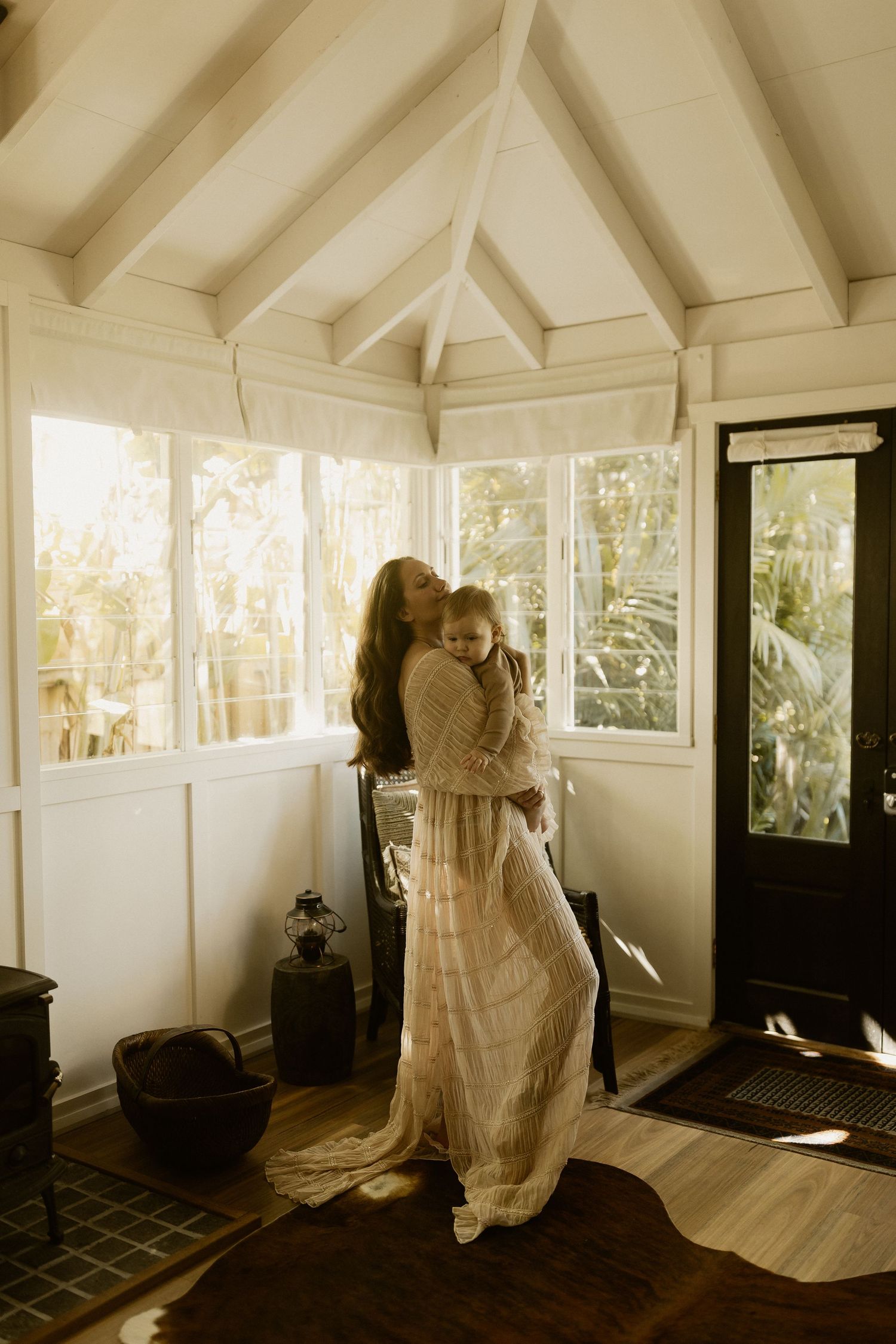 Intimate moment in sunlit room with vaulted white ceiling and dark wood floors.