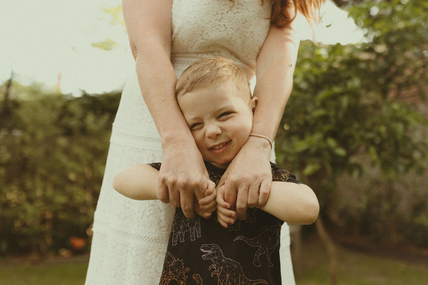 Candid outdoor family photo showing playful interaction and laughter in a garden setting.