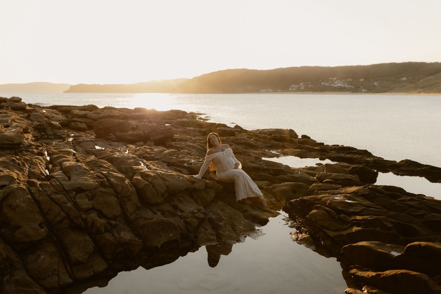 Dramatic coastal landscape with rocky cliffs and ocean waves during golden hour sunset.