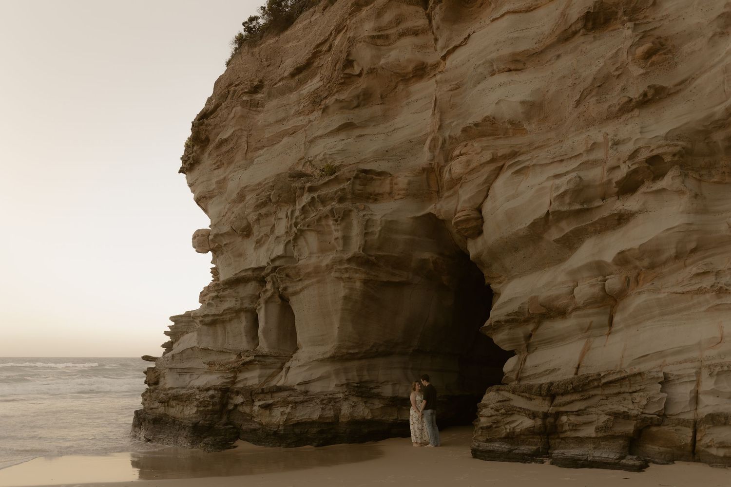 Scenic coastal cliffs with white limestone formations and crashing waves against rocky shores during sunset.
