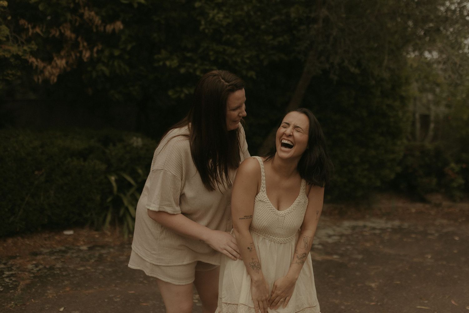 Two people embrace and laugh together in a candid outdoor moment at dusk.