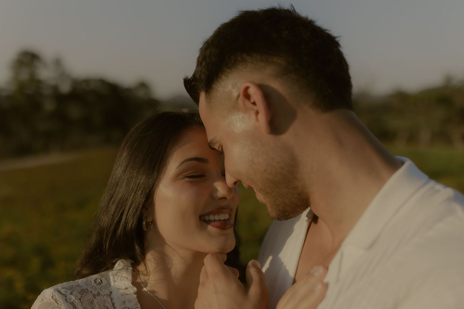 Intimate wedding couple shares tender moments in a rustic outdoor setting with warm lighting.