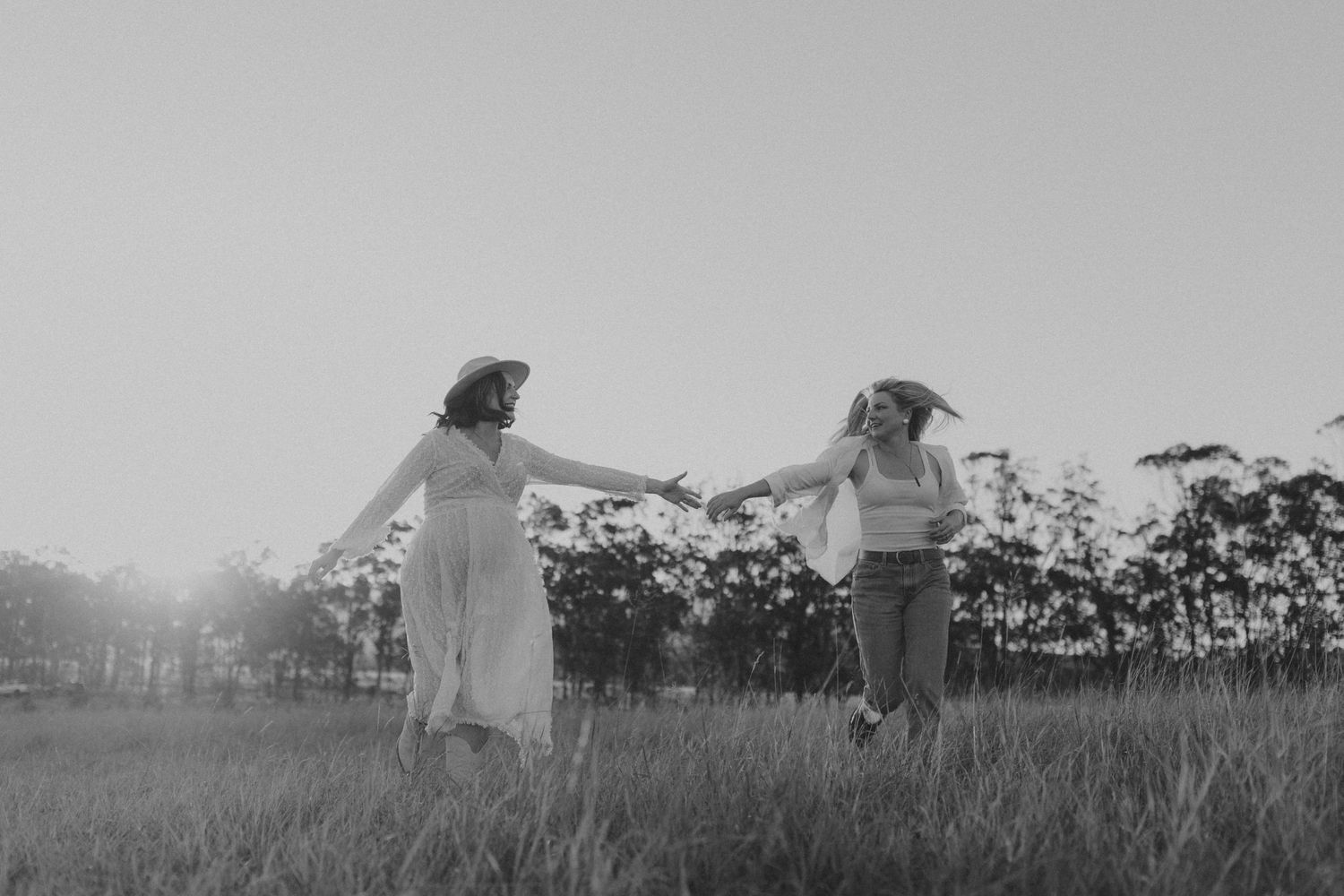 Black and white photograph showing silhouettes sitting together in a grassy meadow.