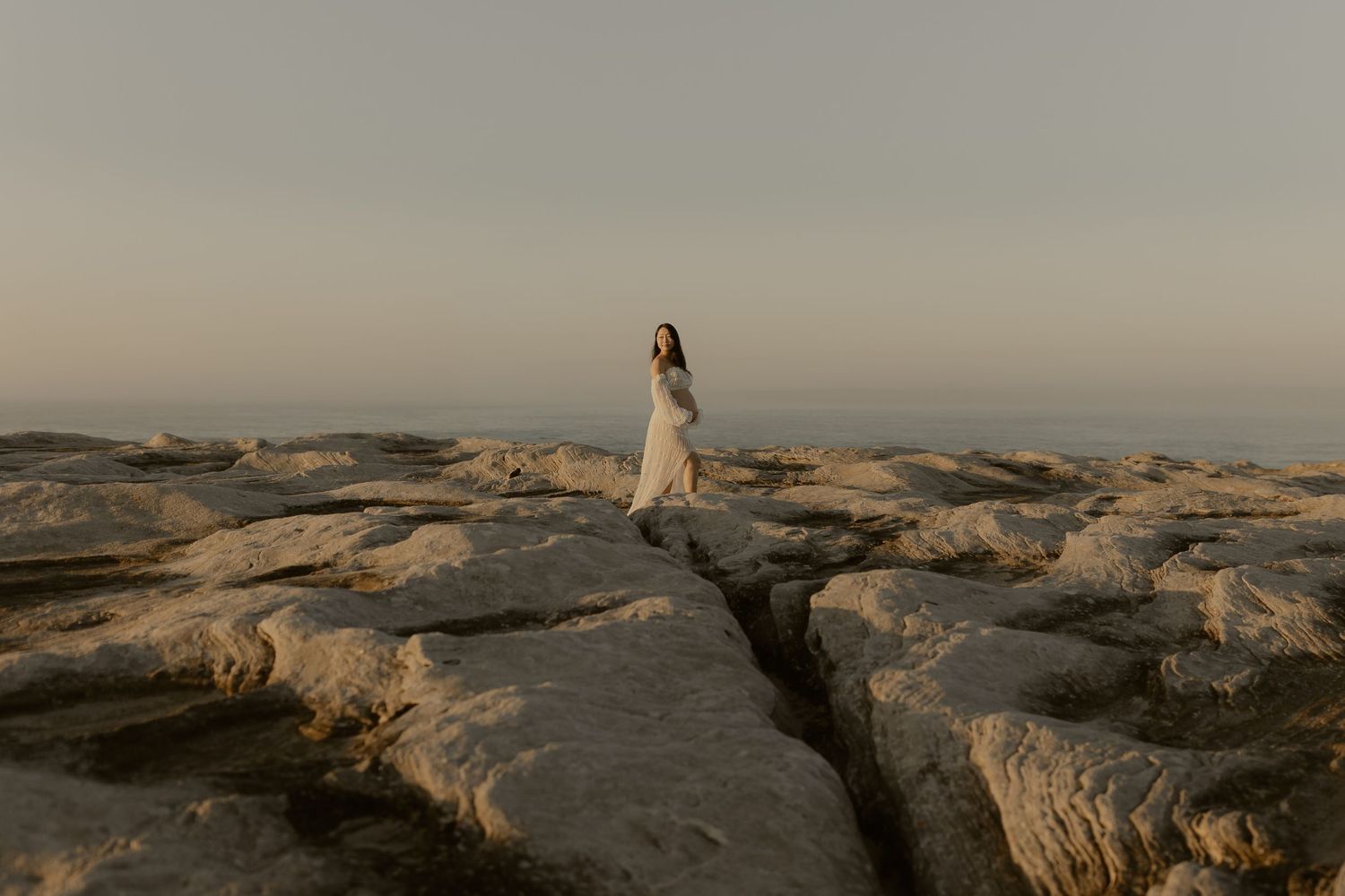 Dramatic coastal landscape with rocky cliffs and ocean waves during golden hour.