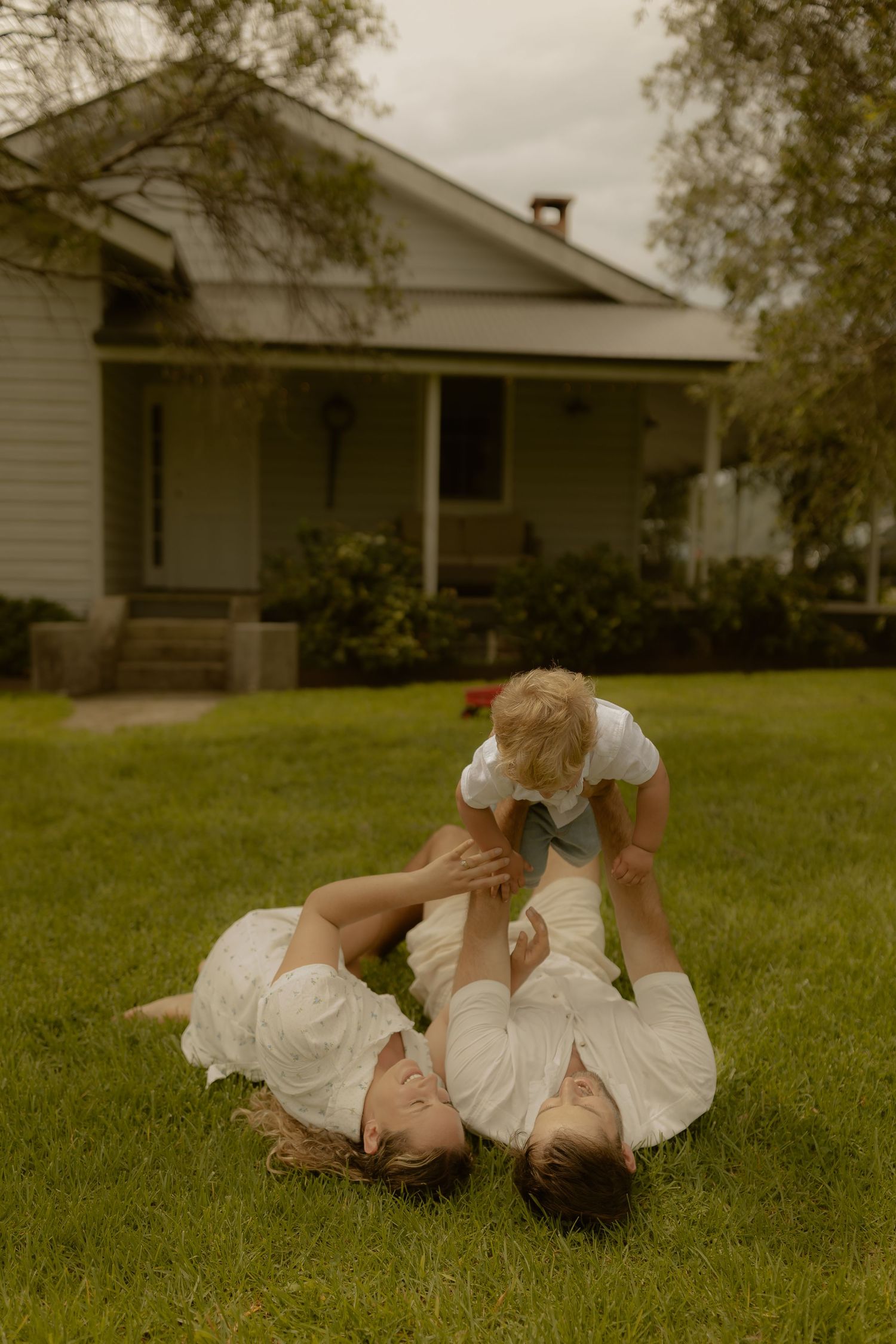 People in white clothing lying and rolling on grass during a warm summer day.